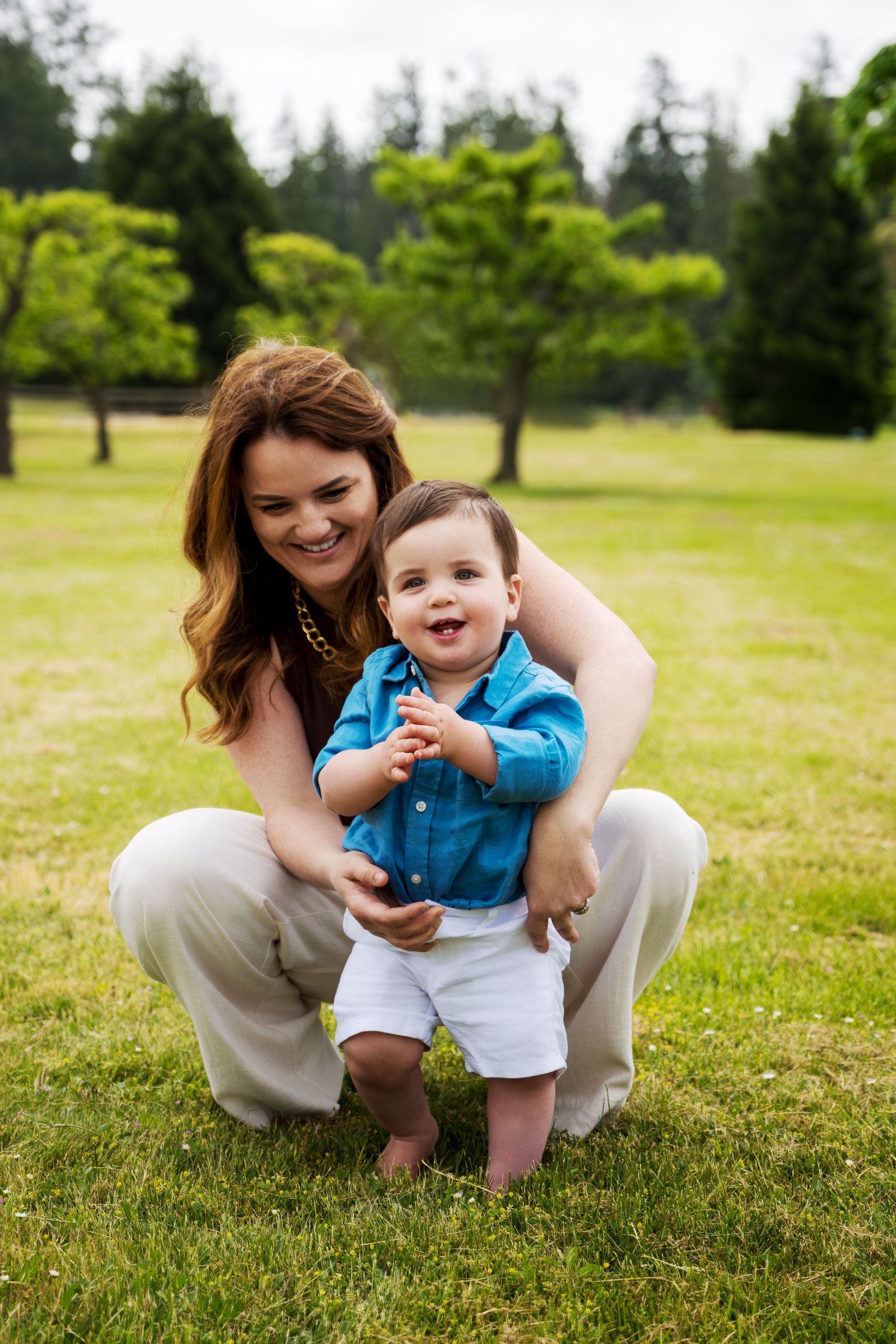 Joyful outdoor portrait of parent and toddler playing on grass.