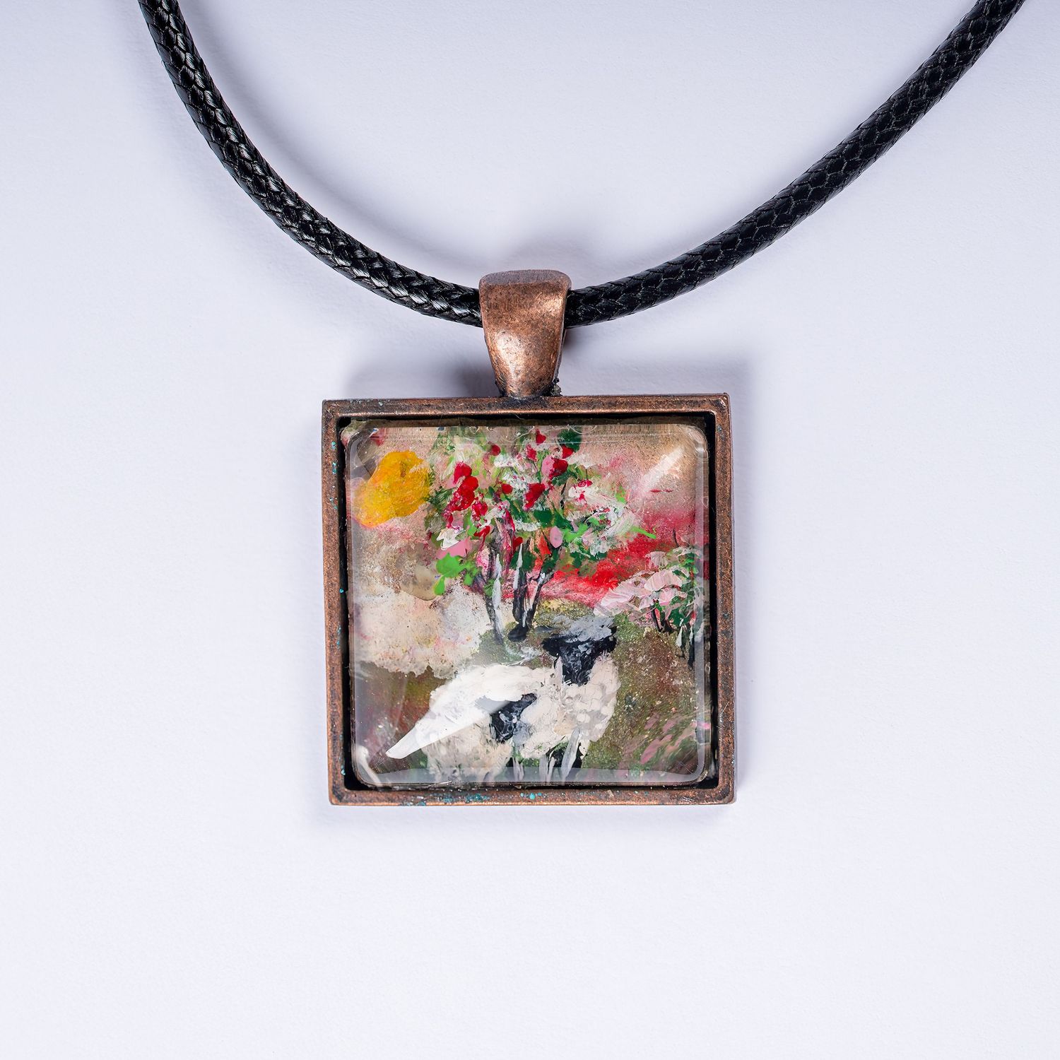Square pendant necklace featuring a vintage watercolor design of sheep and flowers in muted colors with copper frame.