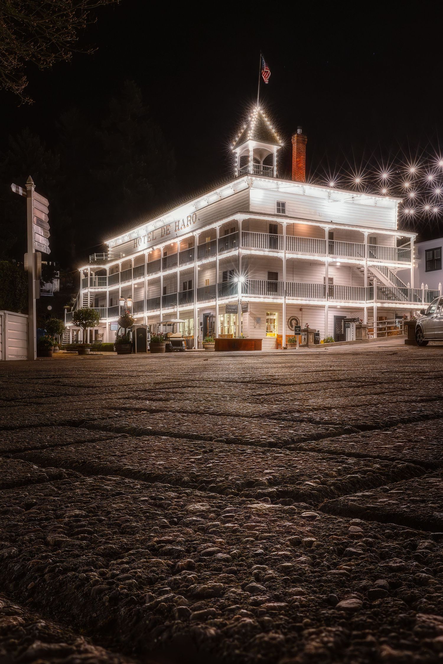 Historic white hotel building illuminated at night with string lights and American flag.