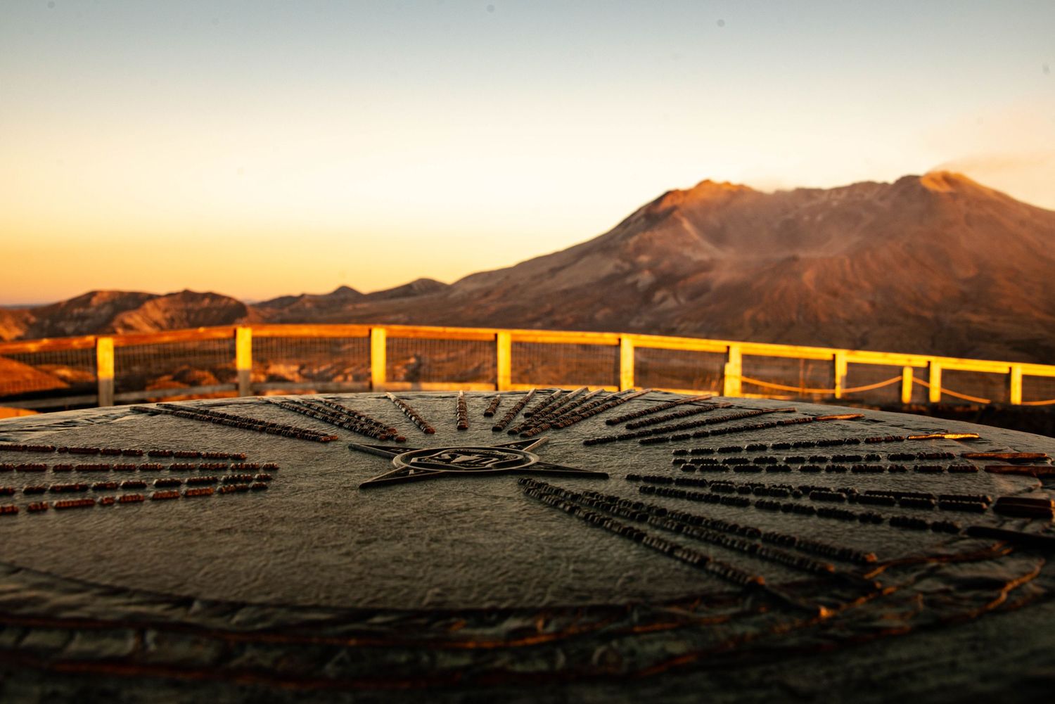 Amphitheater seating faces mountain vista at sunrise with golden light illuminating curved concrete rows.