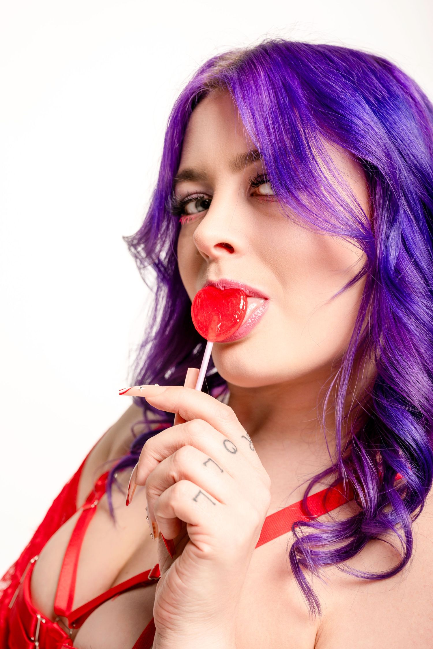 Fashion portrait with vibrant purple hair and heart-shaped lollipop.