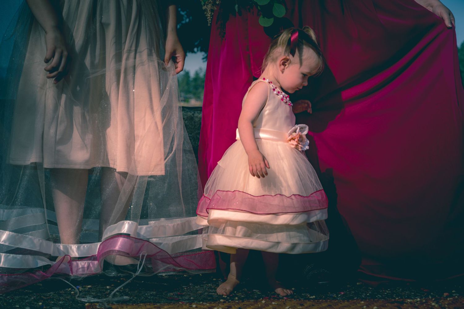 Young child in a pink dress plays behind sheer fabric at a formal event.