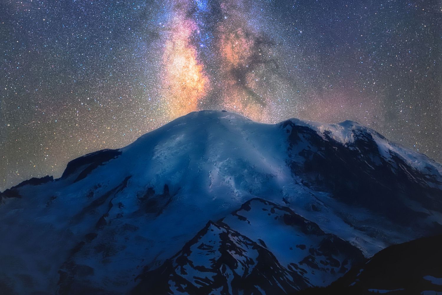 Milky Way galaxy rising over snow-capped mountain peak in dramatic nighttime landscape.