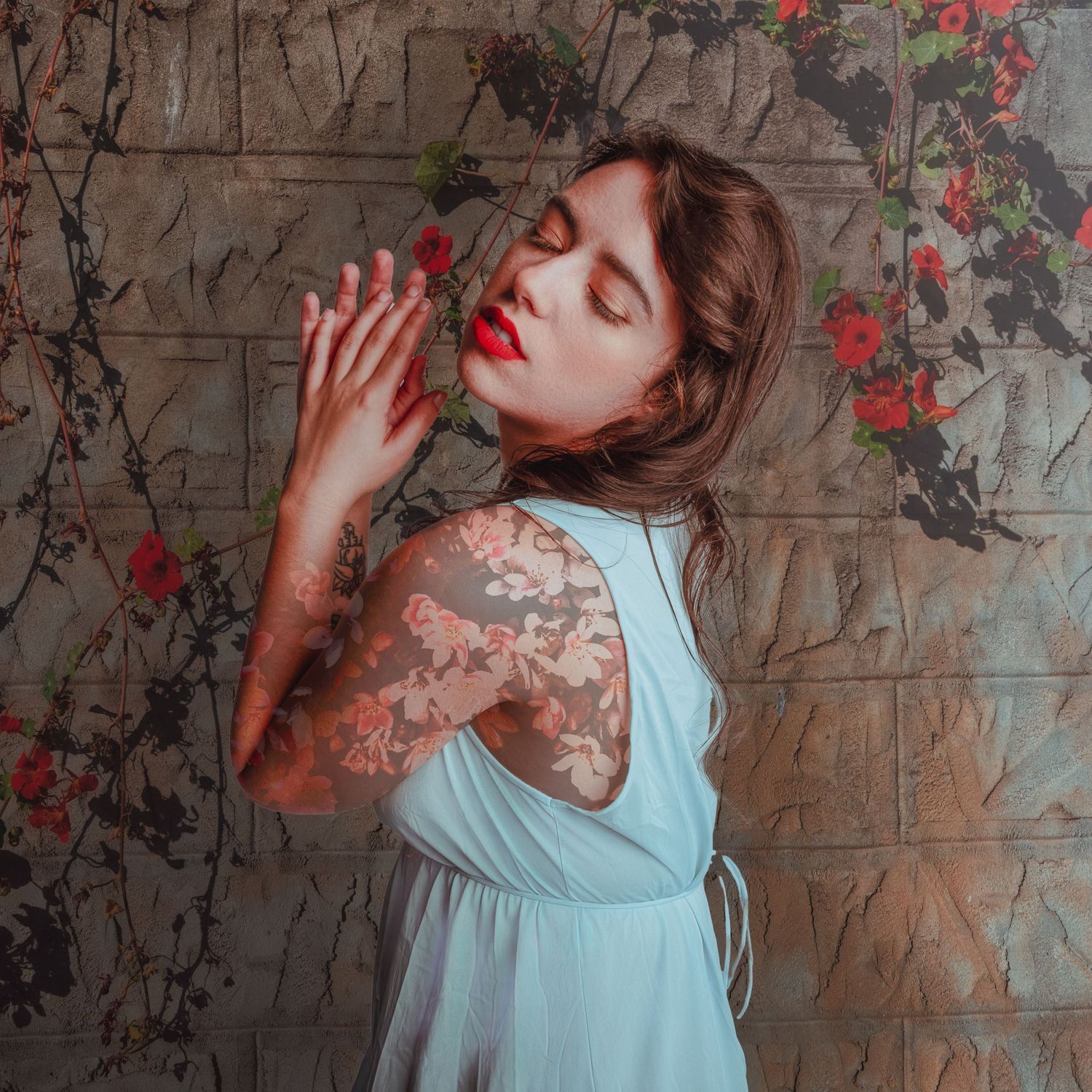 Ethereal portrait against brick wall with climbing roses and delicate blue dress.