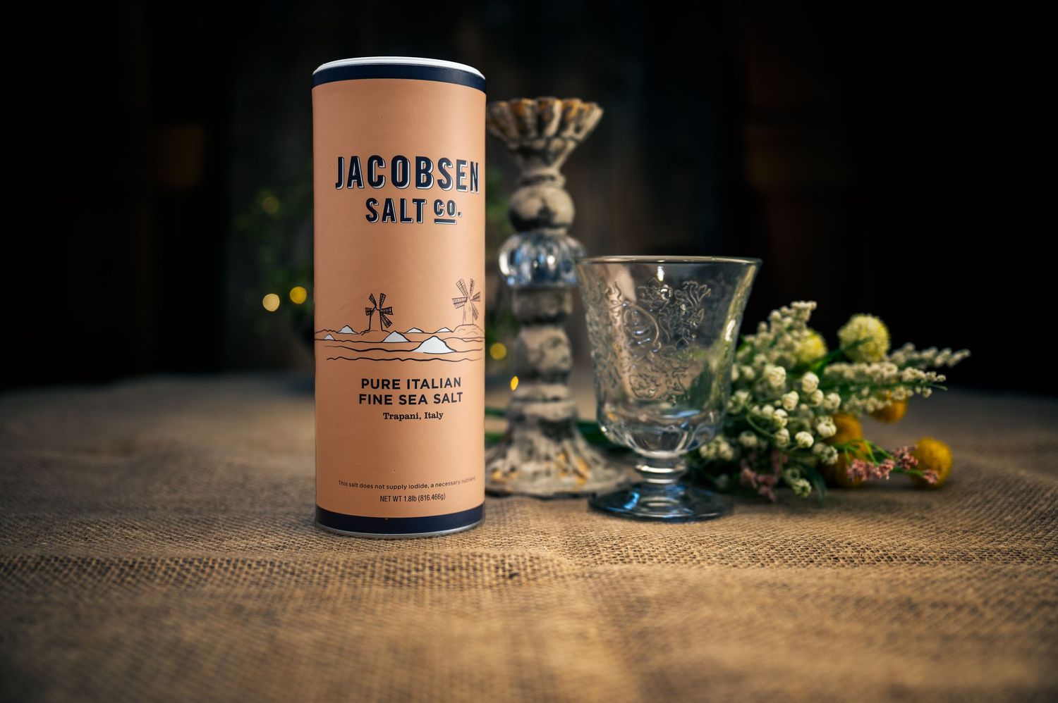 Jacobsen artisanal salt container displayed with vintage glassware and greenery on wooden surface.