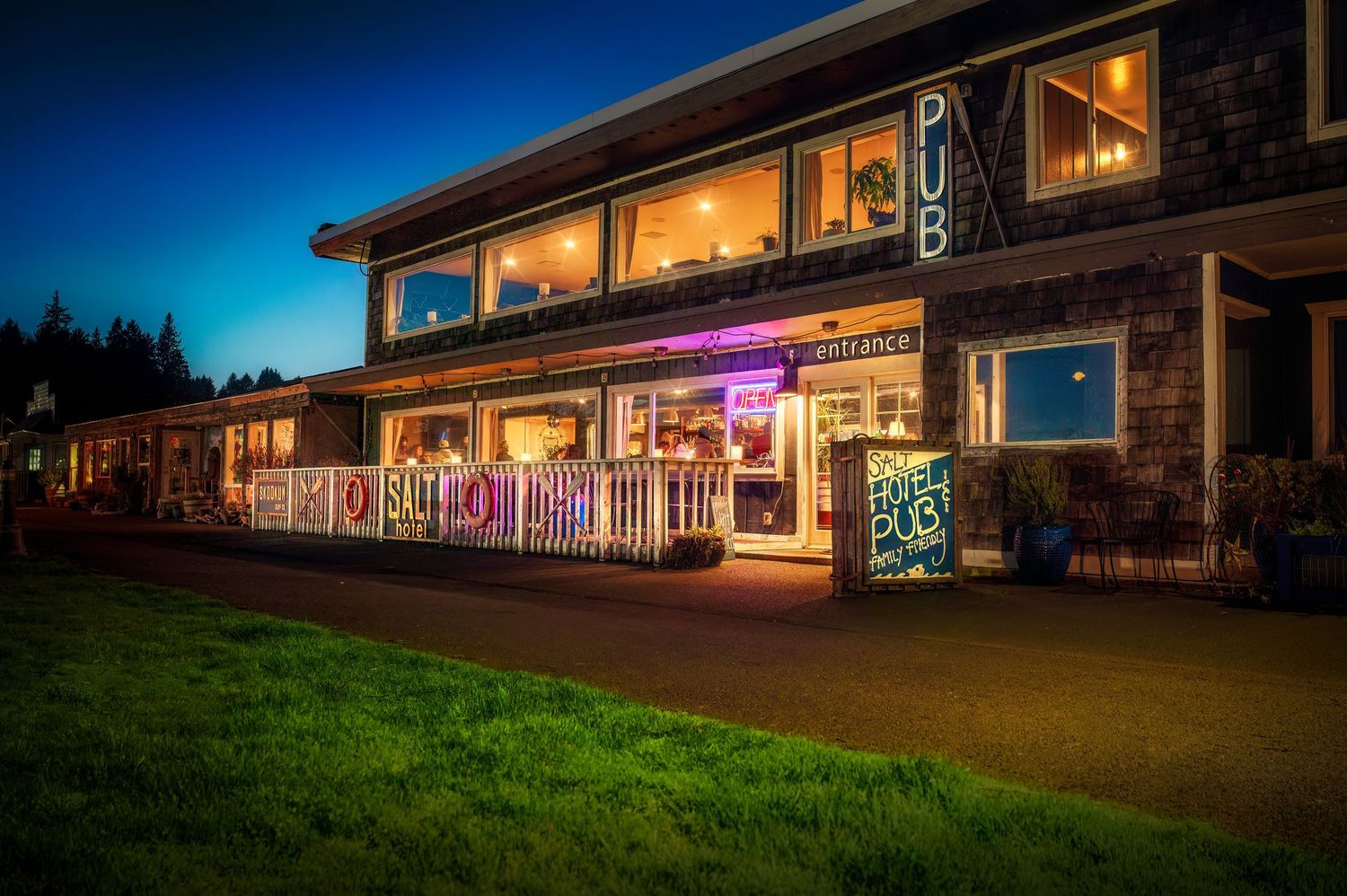 Illuminated storefront with festive lights and covered porch at dusk creates warm evening ambiance.