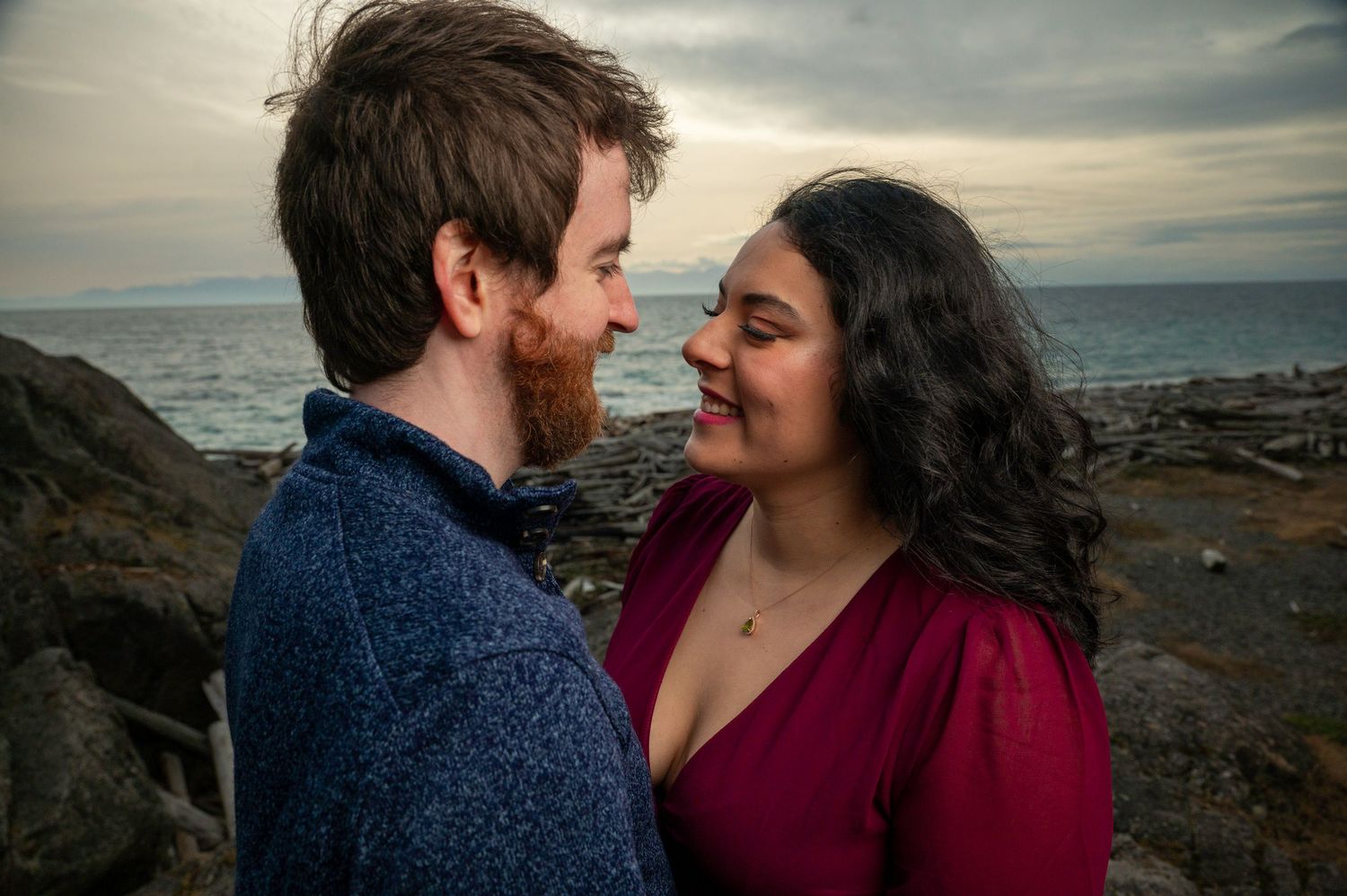 Intimate moment between couple on seaside cliffs during golden hour.