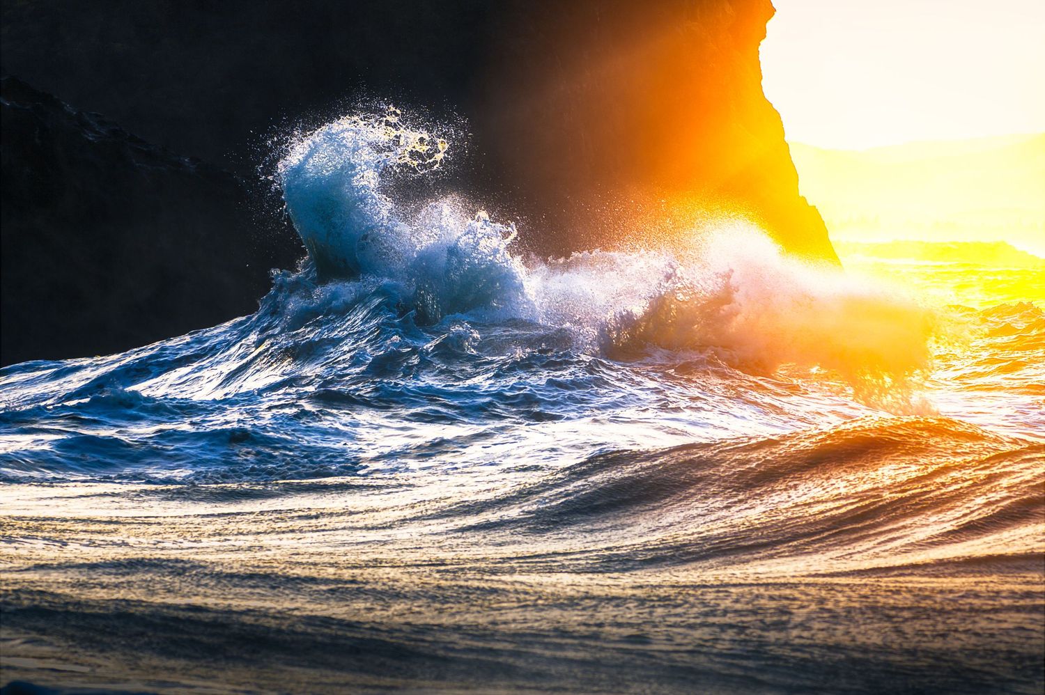 Dramatic ocean wave crashes in golden sunlight creating a spectacular spray at sunset.