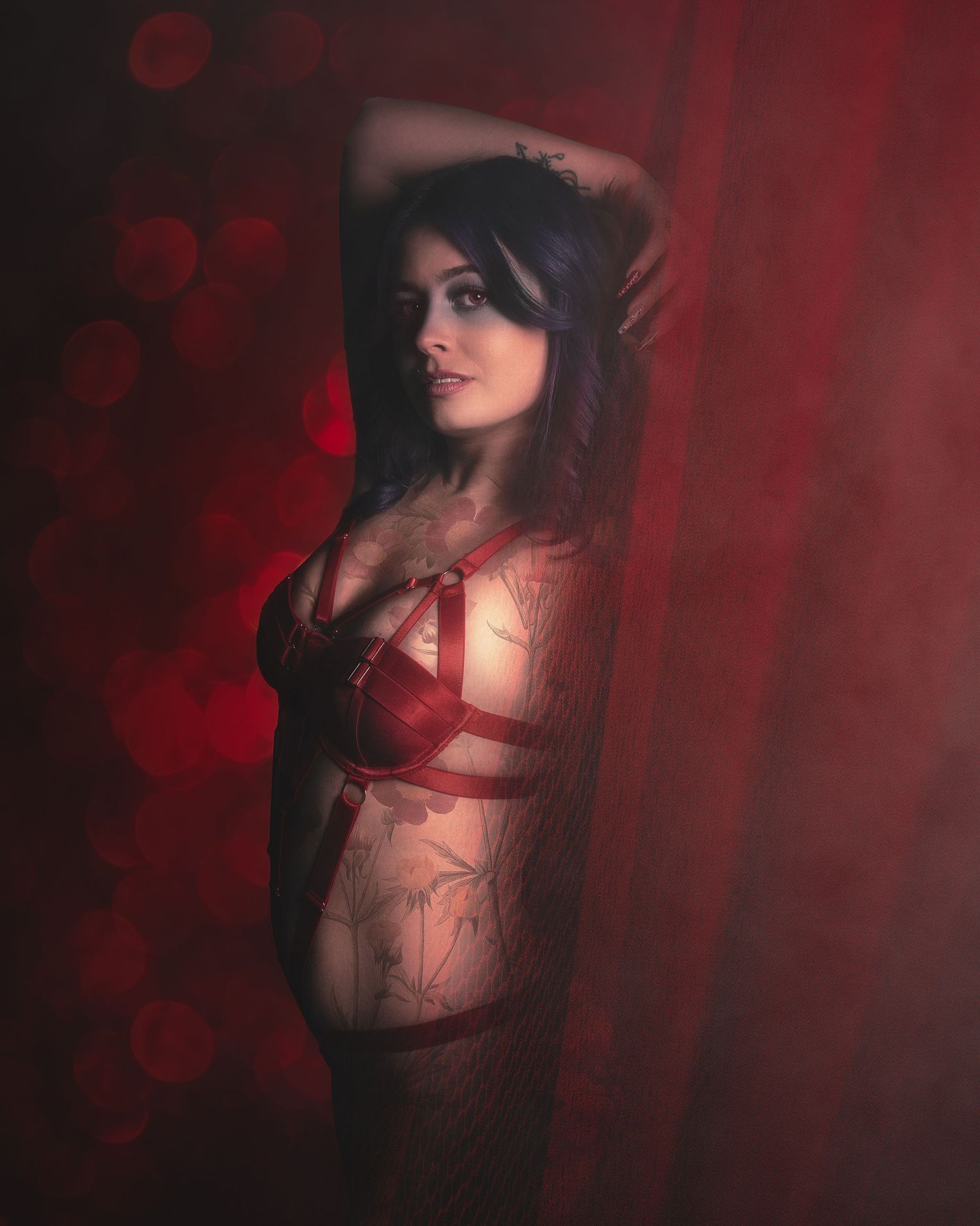 Moody boudoir photography with red lighting and bokeh effects.