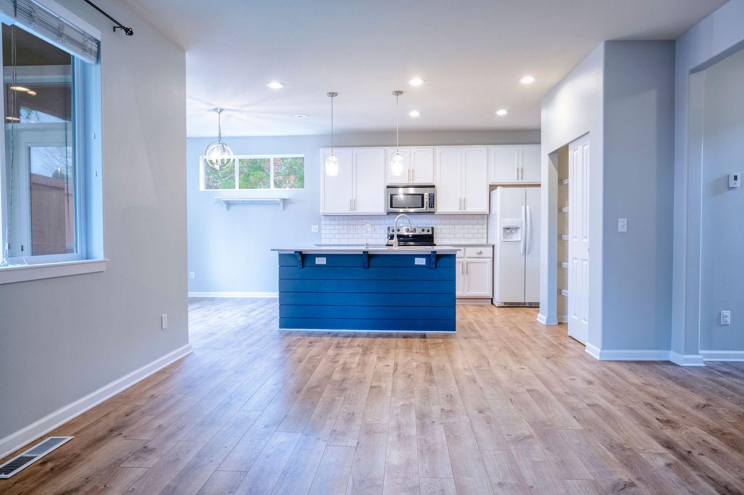 Modern apartment interior with blue kitchen island, white cabinets and hardwood floors.