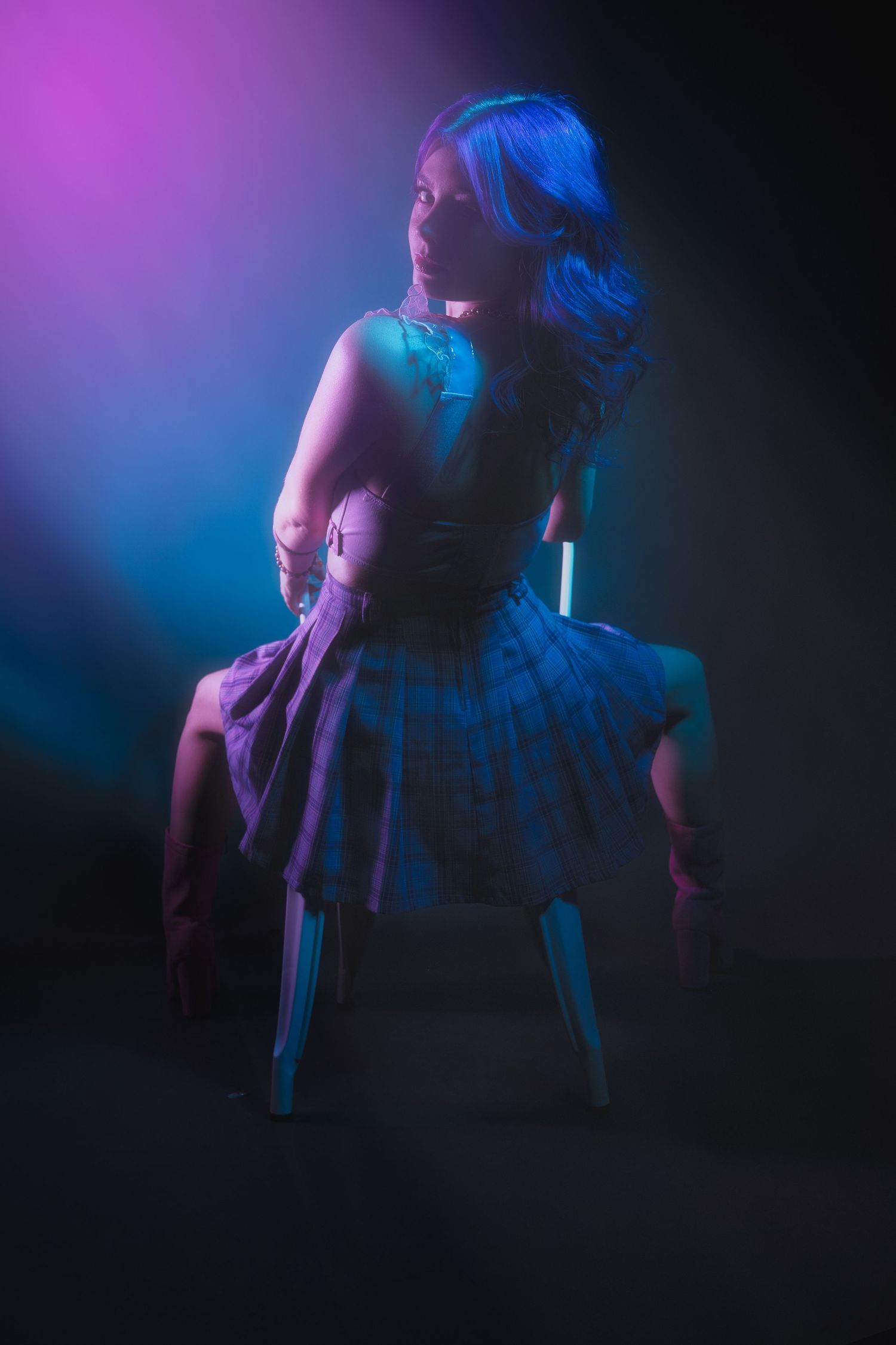 Silhouette on chair with dramatic purple and blue lighting effects.