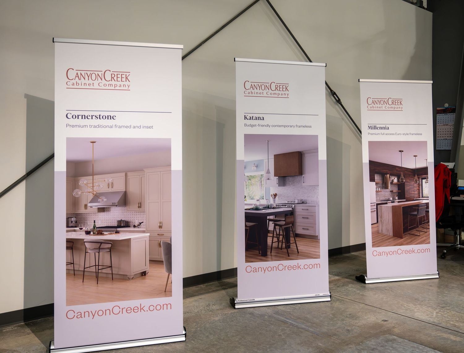 Three promotional banner stands displaying kitchen renovation designs and company branding.