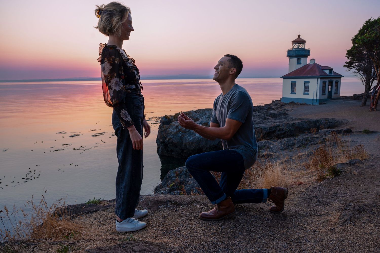 A surprise proposal moment at sunset with lighthouse in background.