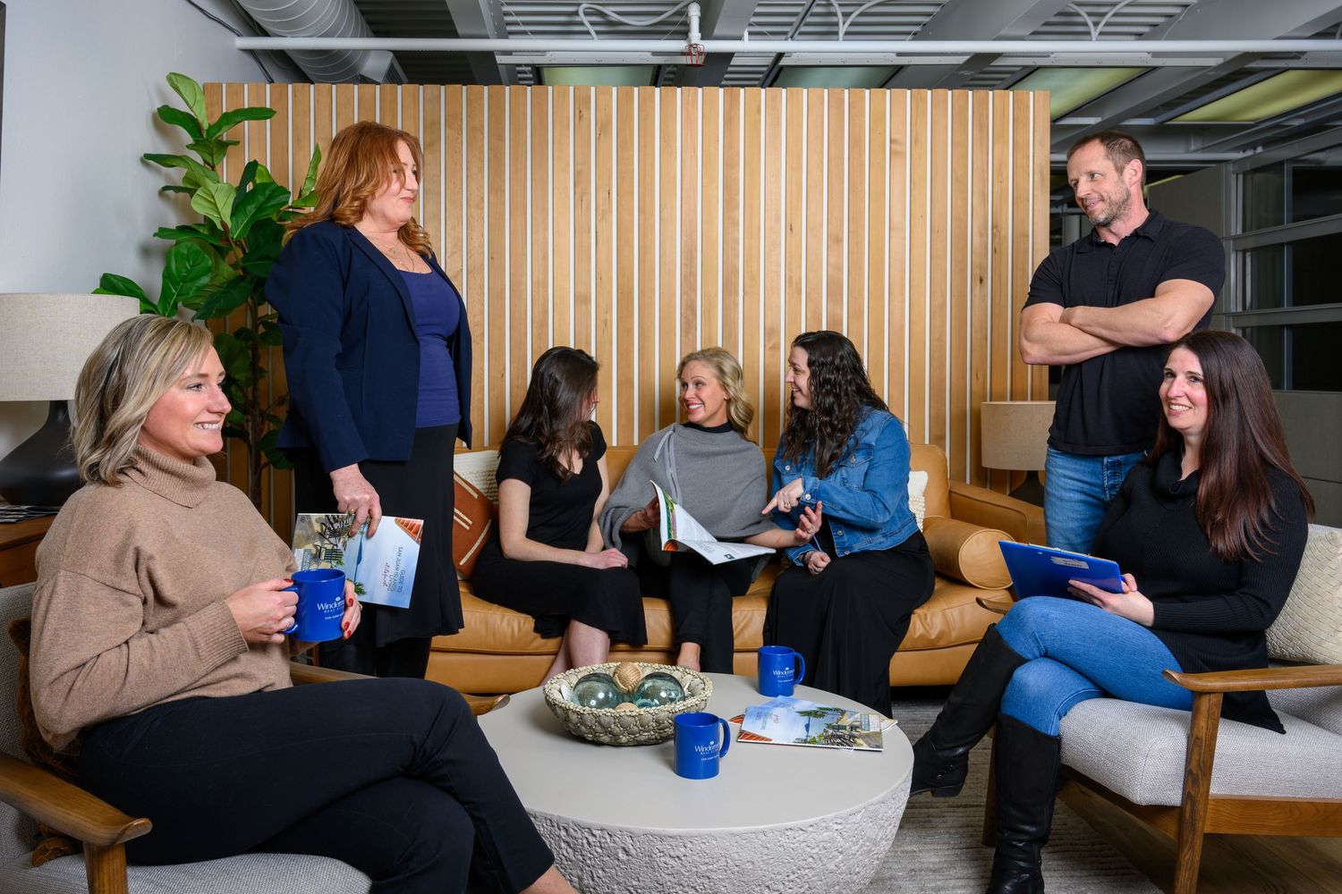 People gathered in a casual office lounge area for an informal meeting with books and refreshments.