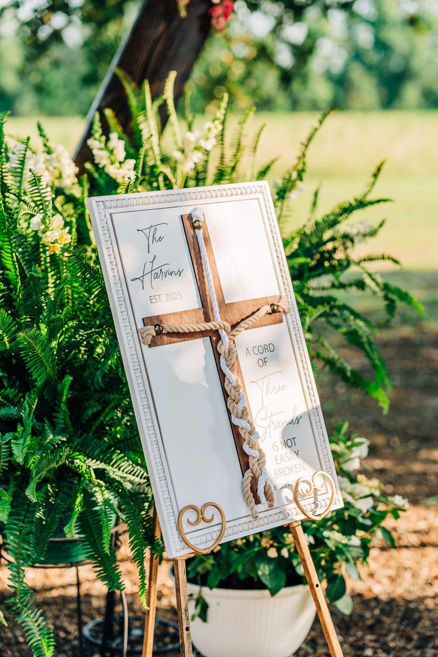 Elegant wedding signage displayed on easels among green foliage at outdoor venue.