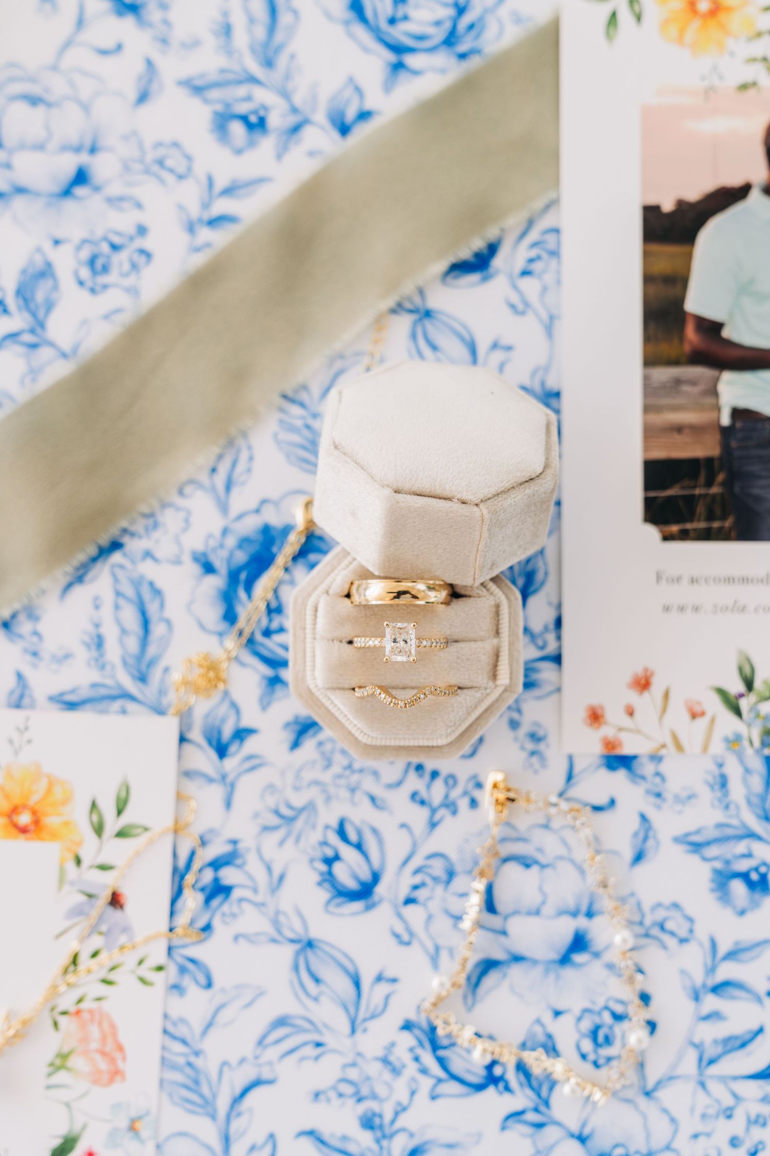 Wedding rings displayed in a velvet ring box on a blue and white floral patterned background.