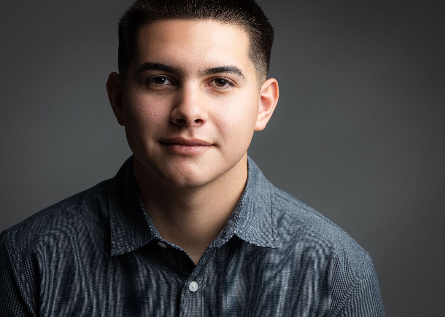 Four artistic black and white studio portraits of a teen in a gray henley shirt against a dark background.