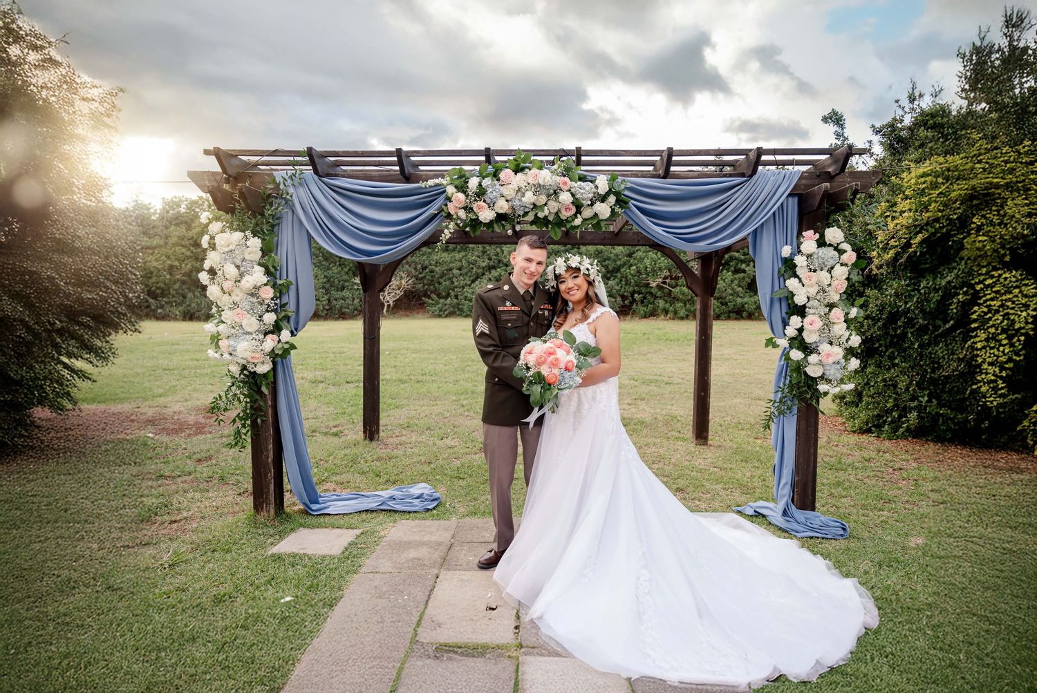 A romantic outdoor wedding ceremony set up with white draped fabric and wooden posts at sunset.