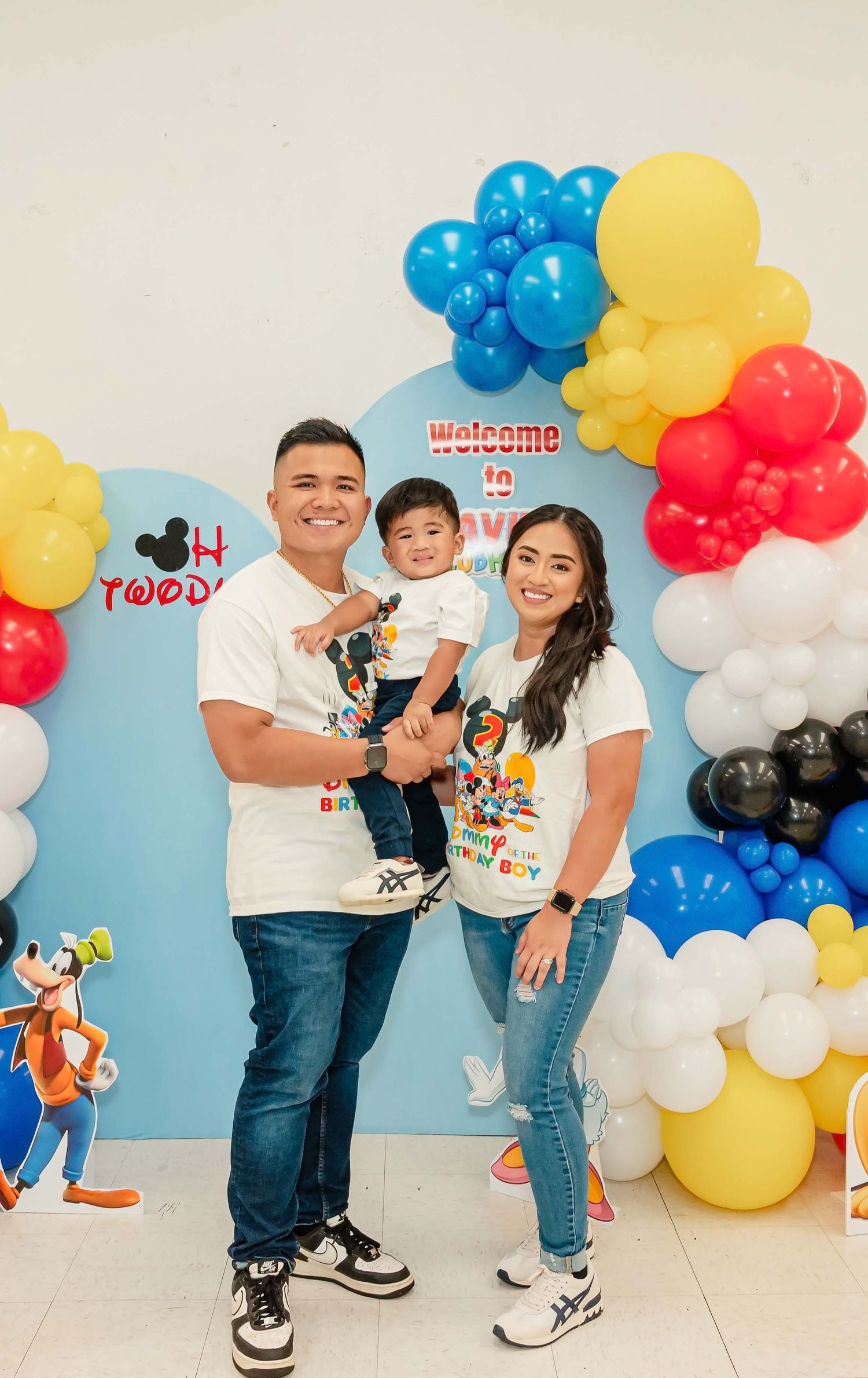 Colorful balloon arch decoration featuring yellow, blue, red and white balloons at a birthday party with Disney theme elements.