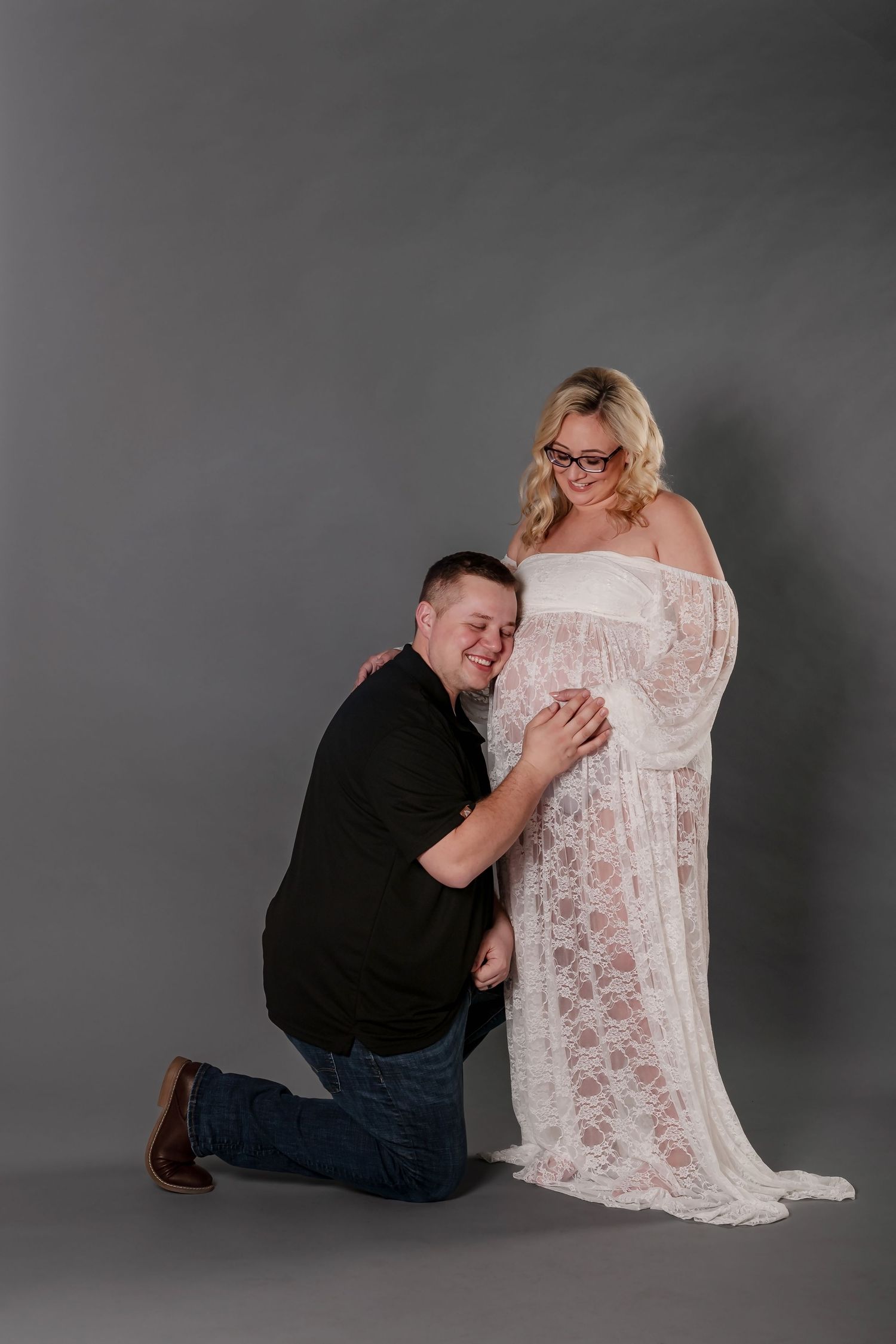 A series of artistic photos capturing someone in a white lace dress kneeling beside a figure in dark clothing against a gray backdrop.