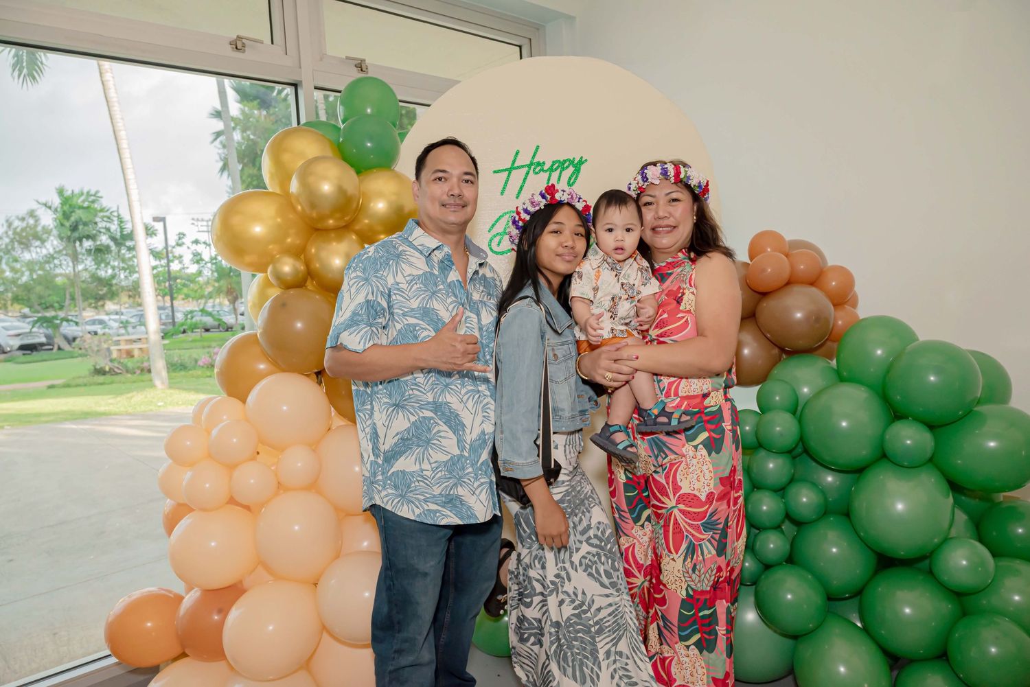 A group celebrates at a party with orange and green balloon decorations in the background.