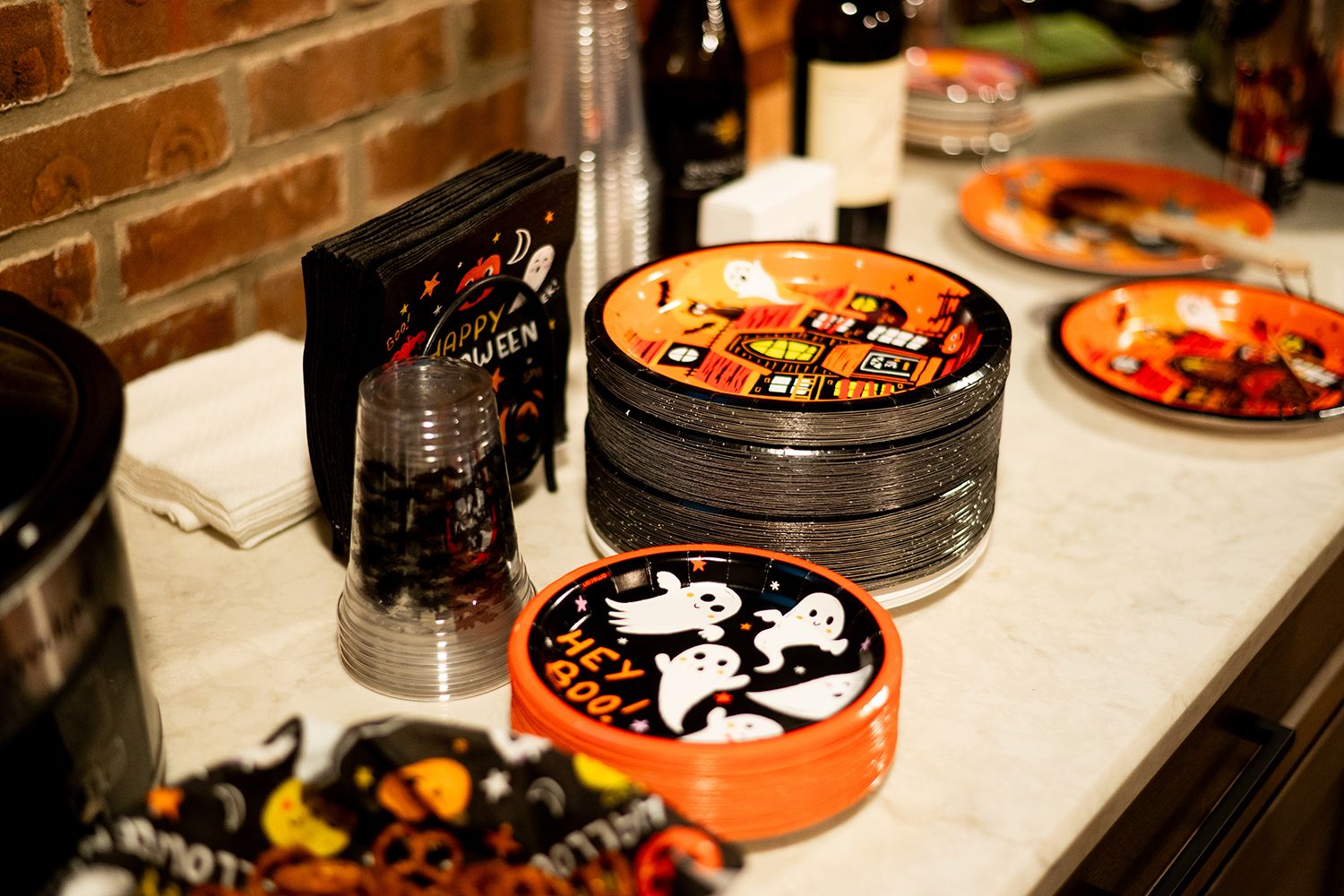 Halloween party table spread with assorted snacks, spooky decorations, and black and orange themed treats arranged on a counter.
