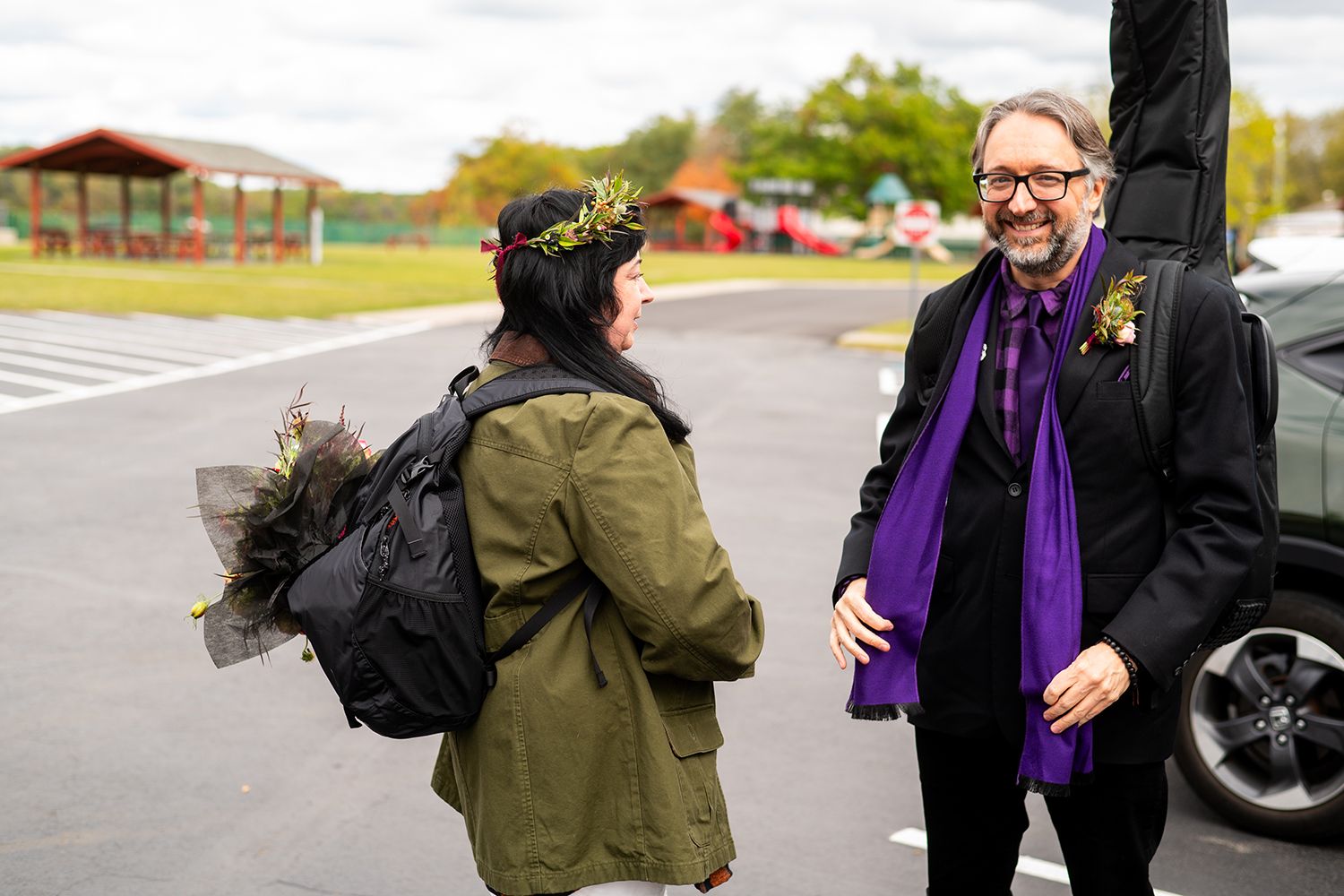 People walking outside on a pathway wearing casual clothing and purple accessories.