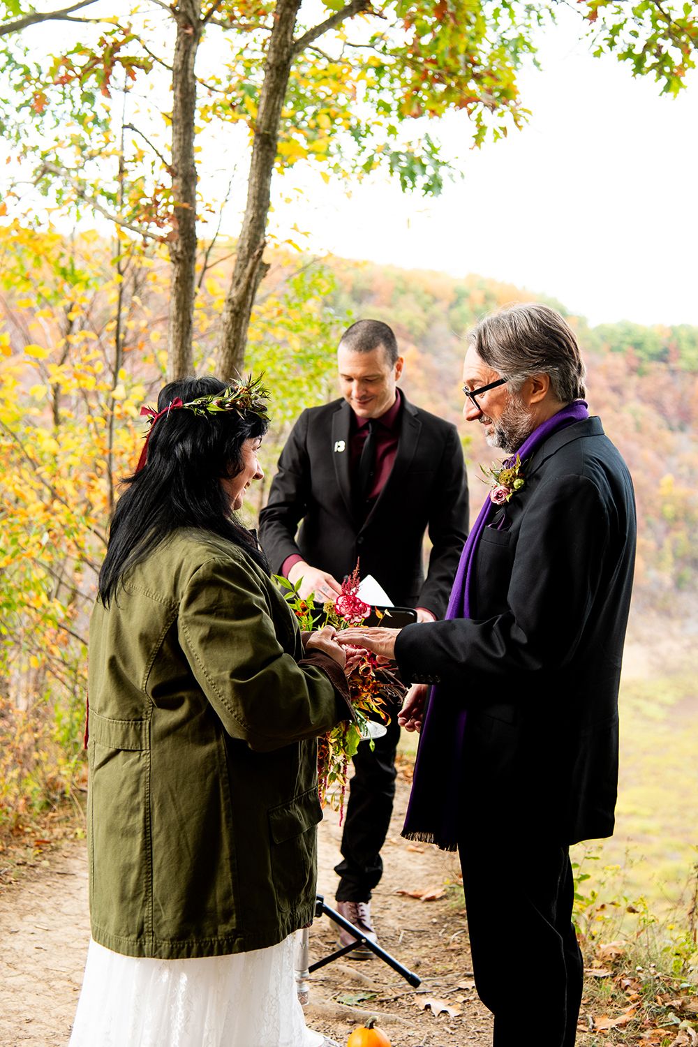 An intimate outdoor wedding ceremony with autumn trees and mountains in the background.