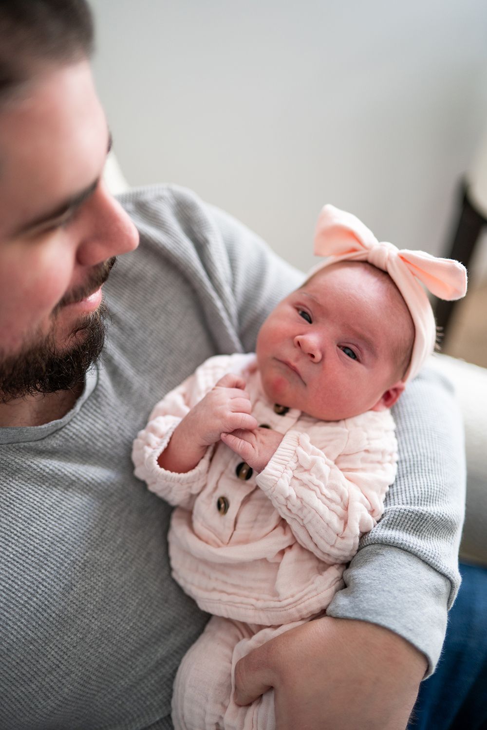 Close-up series of parent cradling newborn baby dressed in pink outfit.