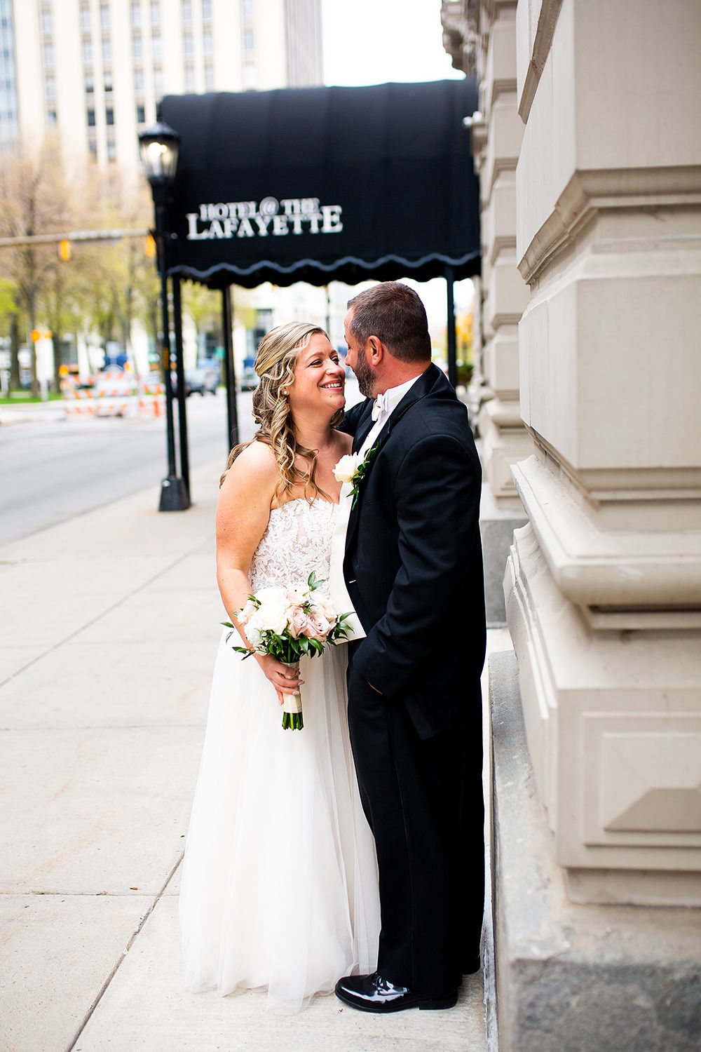 Wedding couple shares intimate moments in a series of romantic outdoor portraits along a classic building facade.