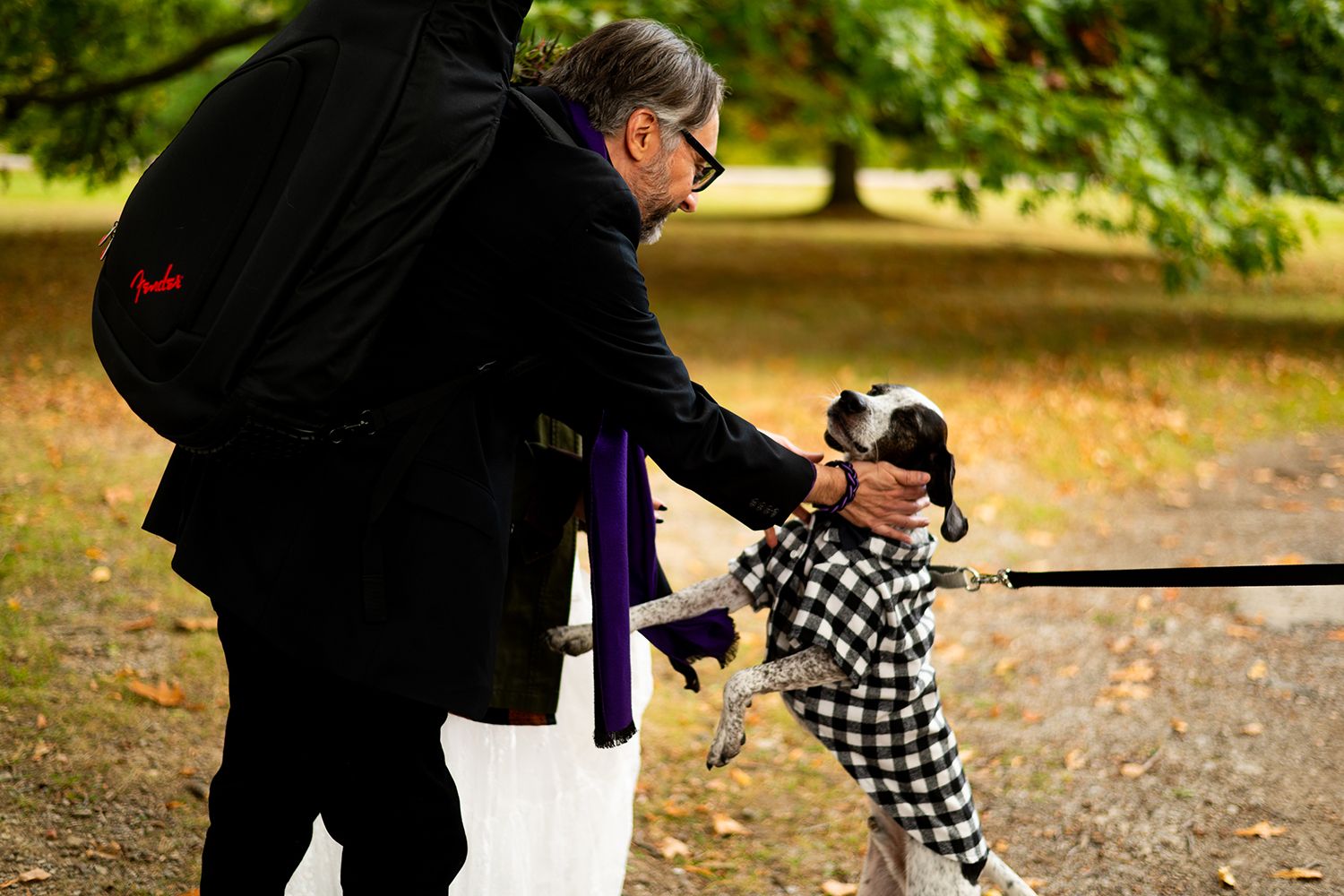 An adult and child enjoy a playful moment together on an autumn day in a park setting.