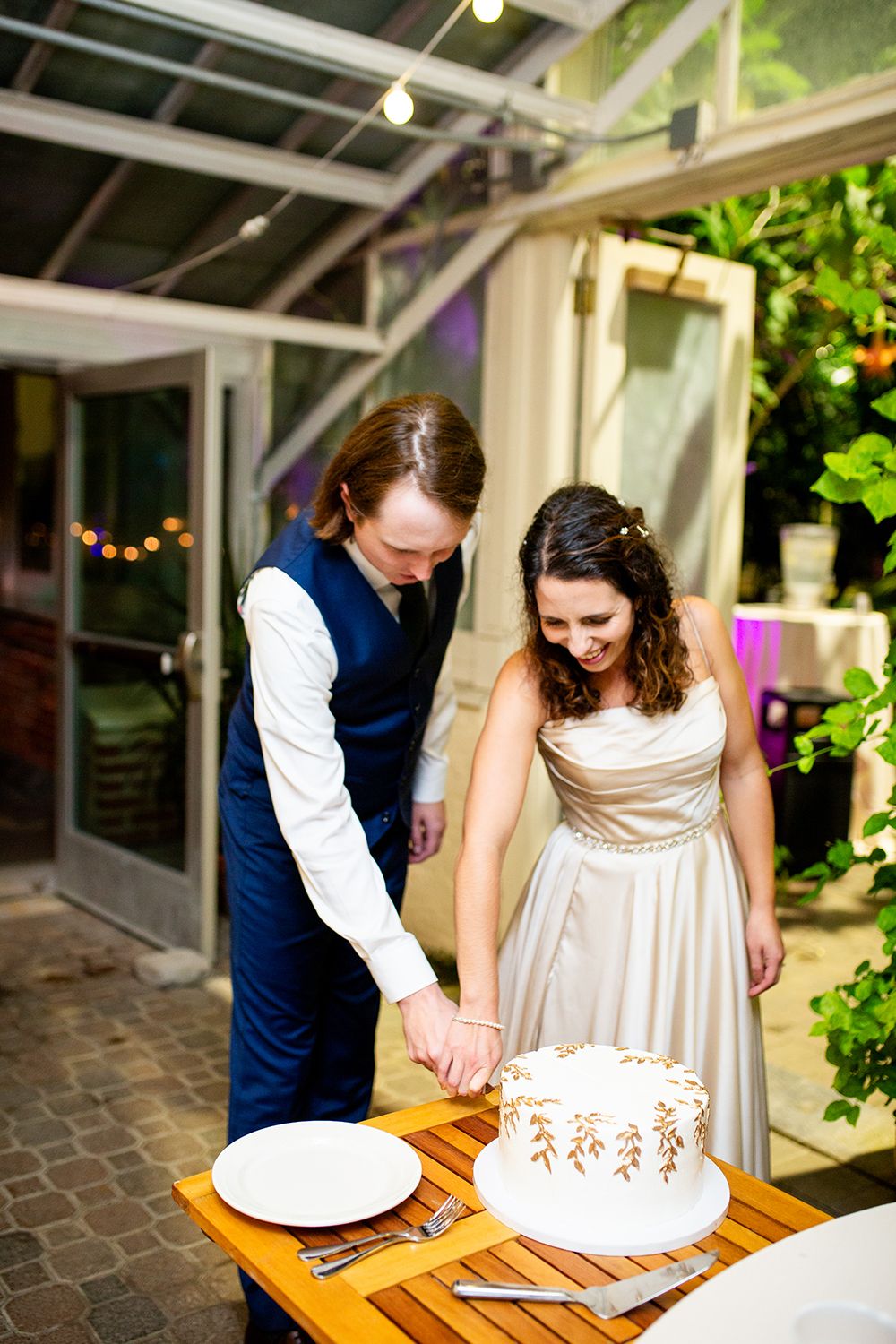 A couple cuts their elegant white wedding cake together at their reception.
