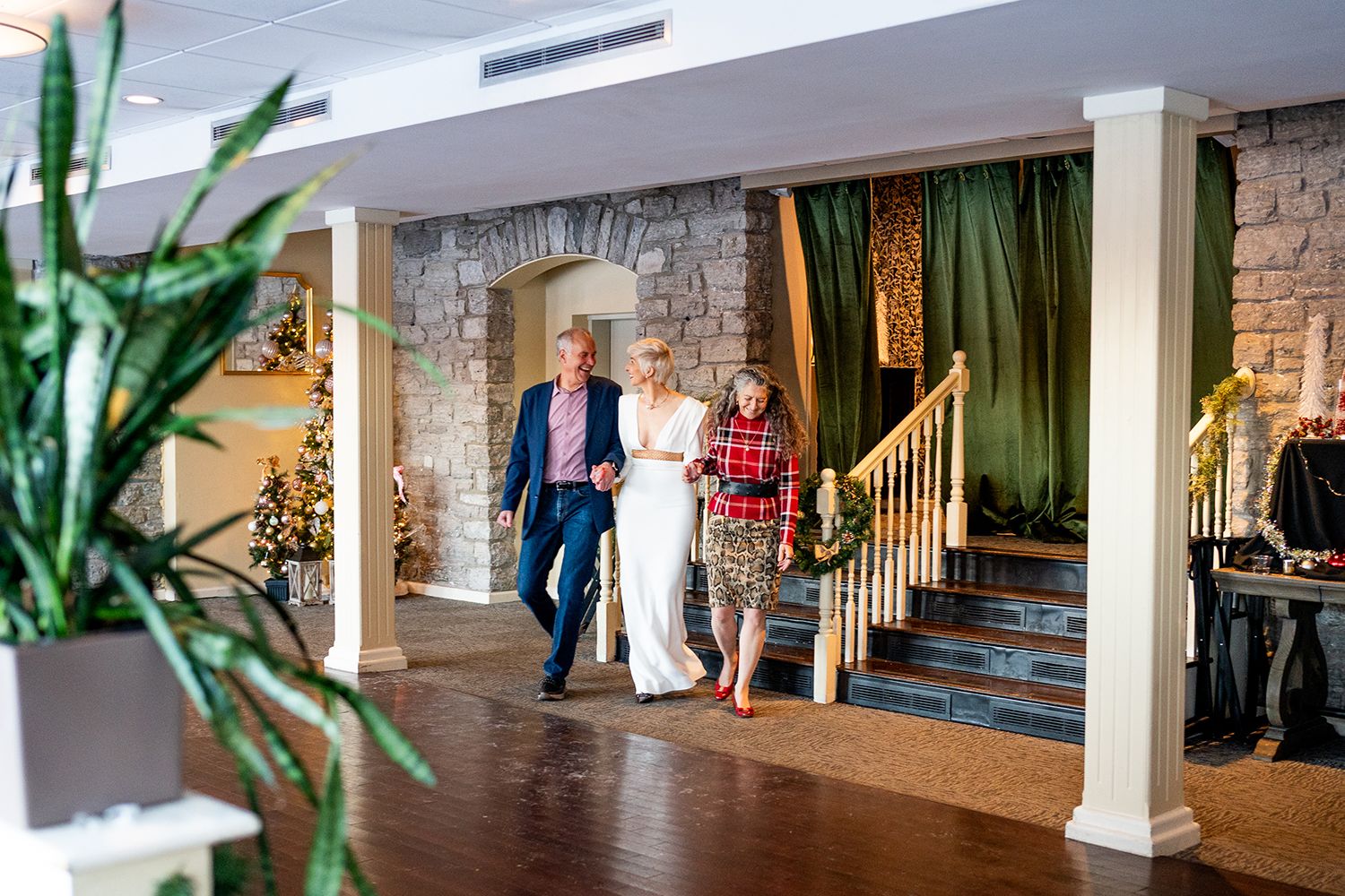 An elegant indoor wedding venue with exposed brick walls, white columns and natural lighting through large windows.