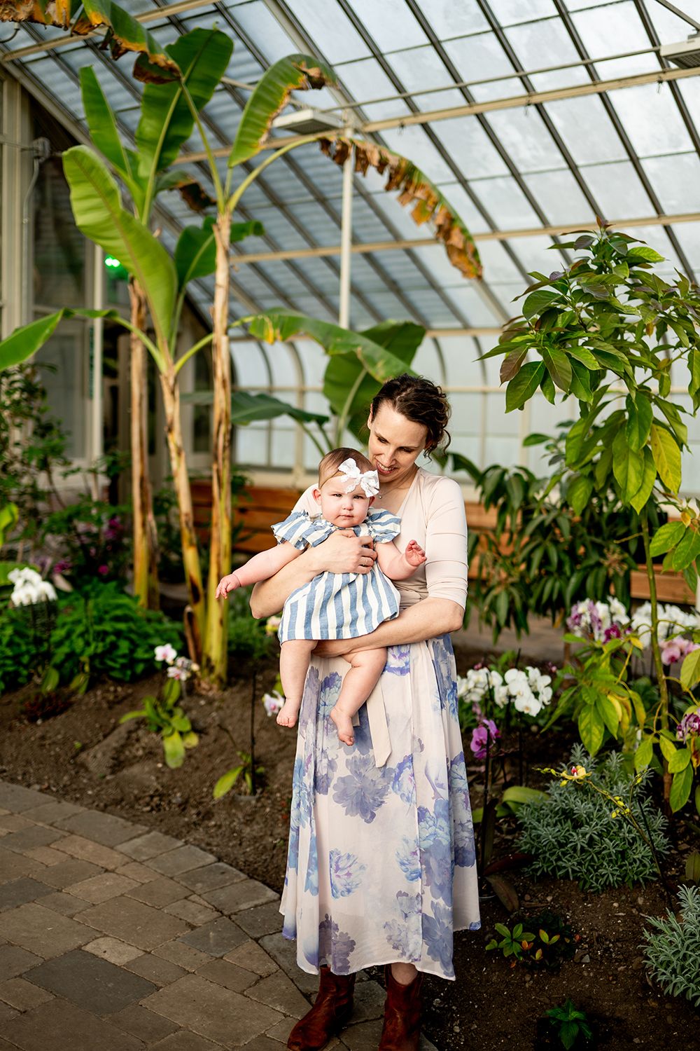 Mother and child share loving embraces in a tropical greenhouse filled with lush plants and flowers.