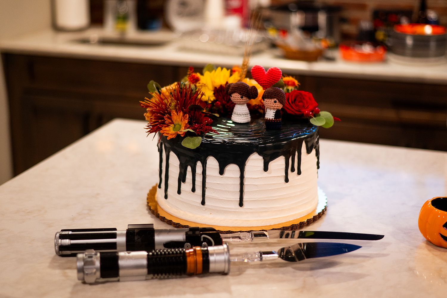 A close-up view of orange and red fall flowers arranged in a decorative display with vintage bottles on a wooden surface.