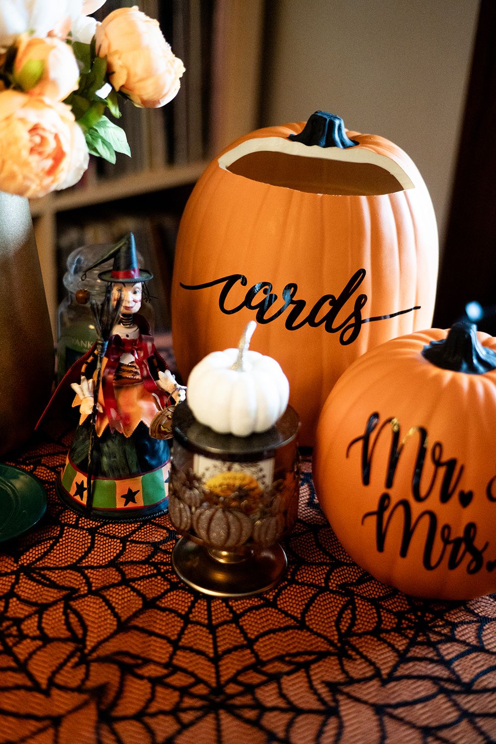 Halloween wedding decorations featuring orange pumpkins, black lace tablecloth, and floral accents create a spooky elegant setting.