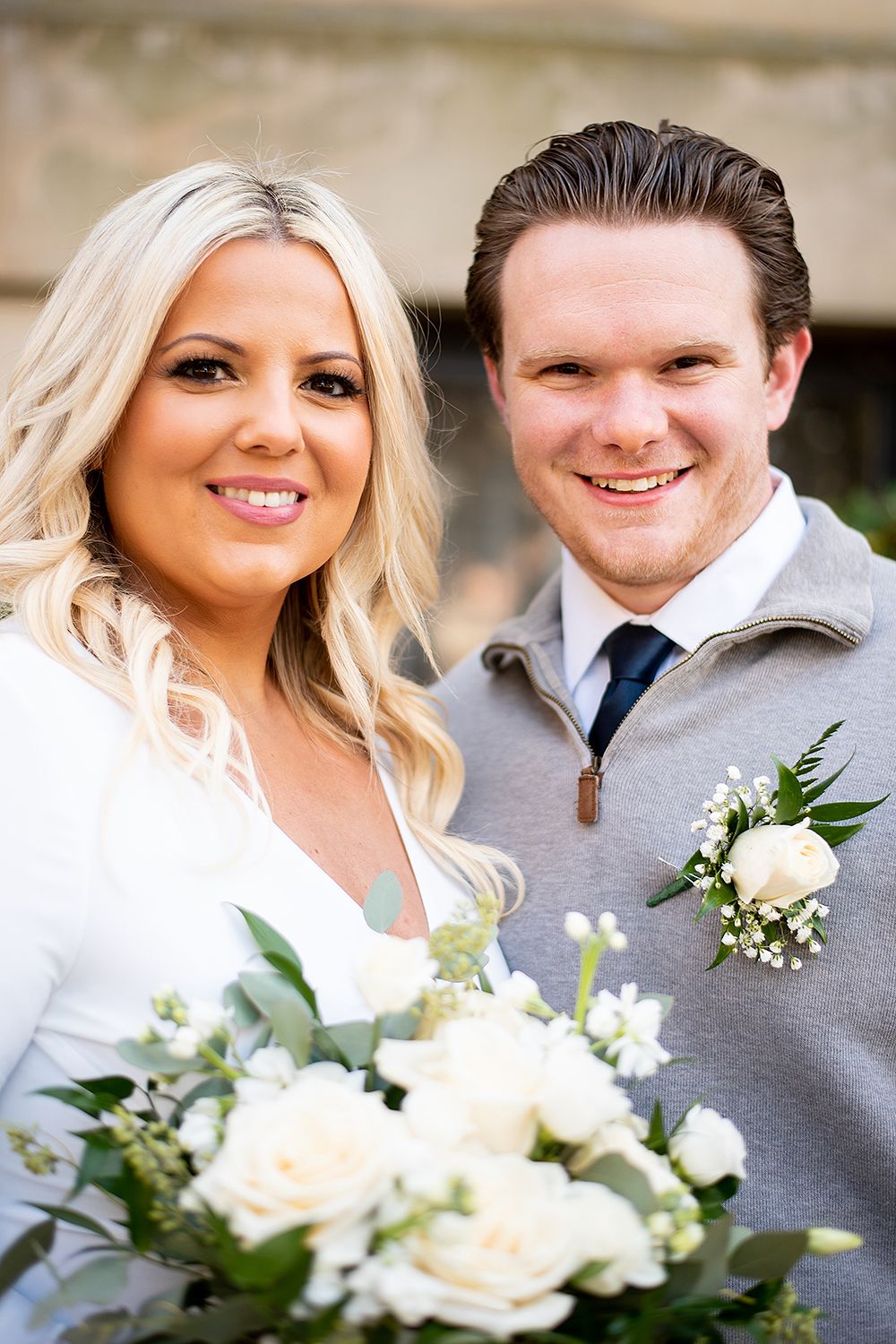 Close-up portrait of a couple dressed in formal attire with white roses and baby's breath floral boutonniere.