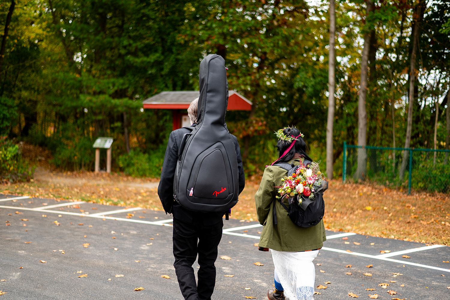 People walking in a parking lot with fall foliage and trees in the background.
