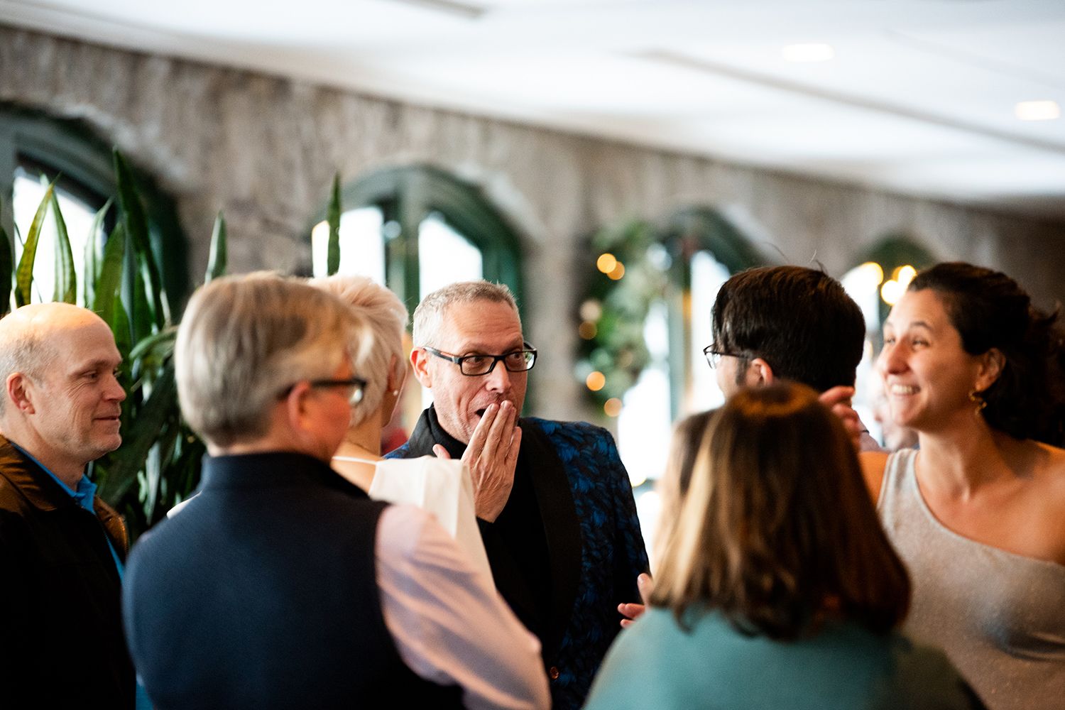 Blurred candid shot of party guests mingling and socializing at an indoor celebration.