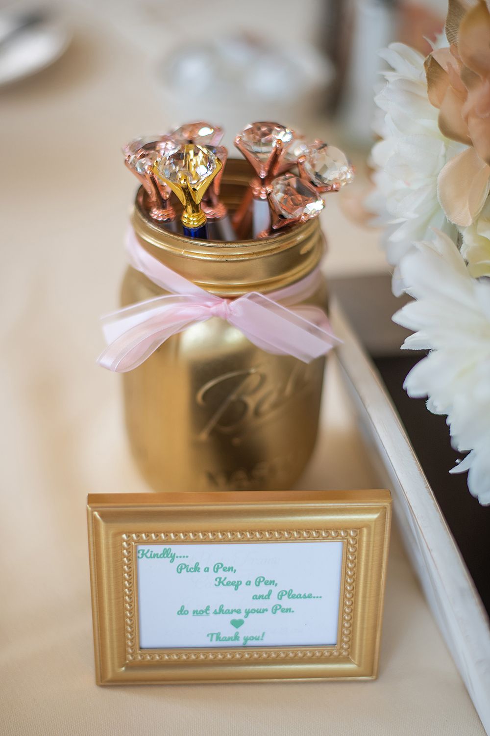 Gold-framed table cards with mint and pink accents displayed at a wedding reception.