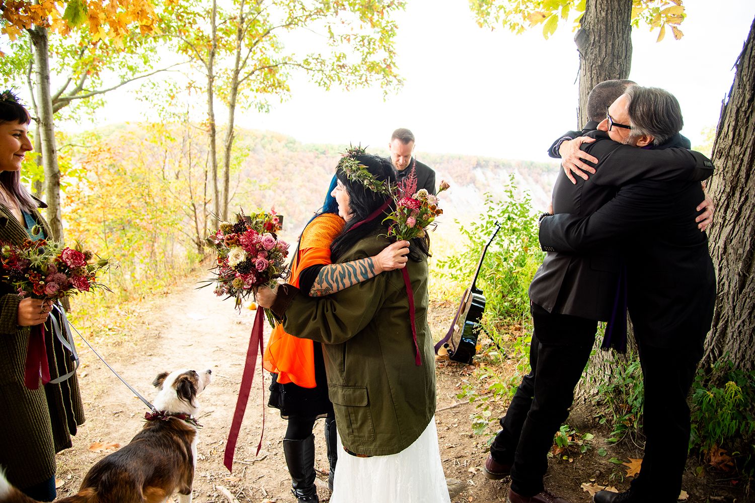 People embrace on an autumn day in the woods with beautiful fall foliage and floral decorations.