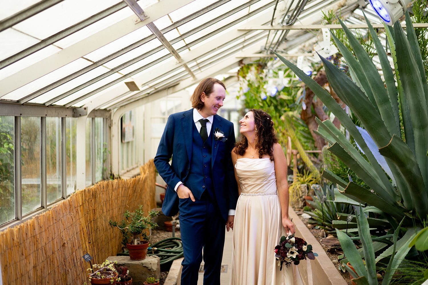 Greenhouse wedding ceremony with glass ceiling, lush tropical plants, and natural lighting creating a romantic atmosphere.