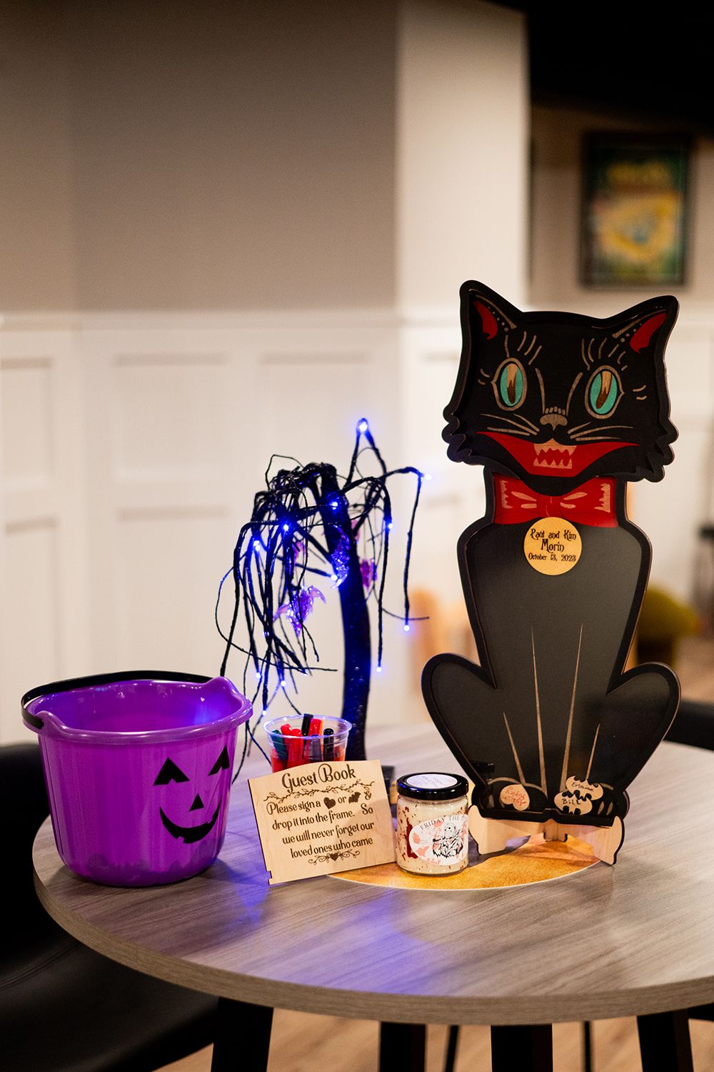Halloween decorations featuring purple bowls, black cat silhouettes, and spooky spiders arranged on a gray table.