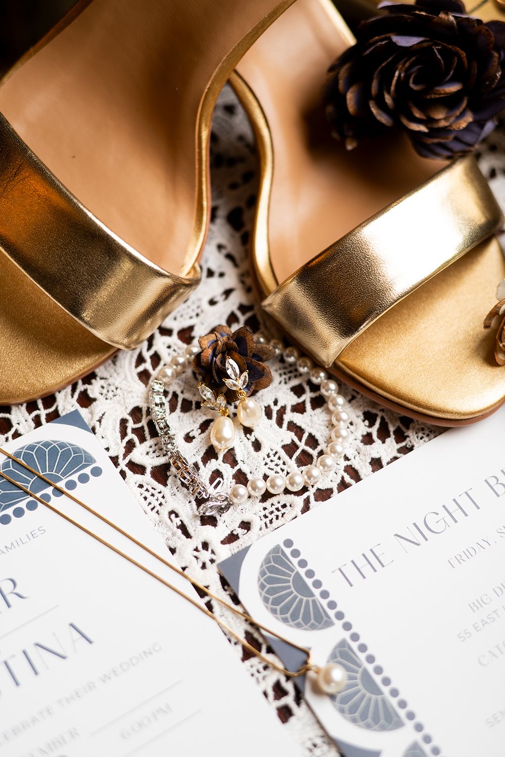 Gold wedding shoes and a decorative invitation with black lace details and blue art deco elements.