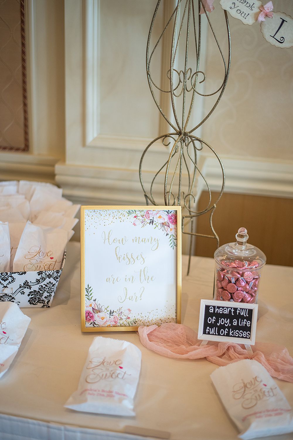 Close-up of wedding table decor featuring wire stands, small chalkboard signs, and pink accents.