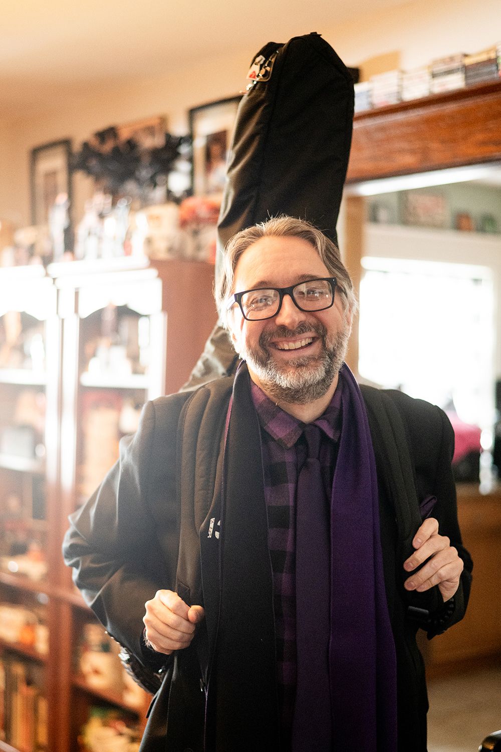 Warm-toned indoor portrait series showing casual expressions while wearing a black jacket and purple scarf.