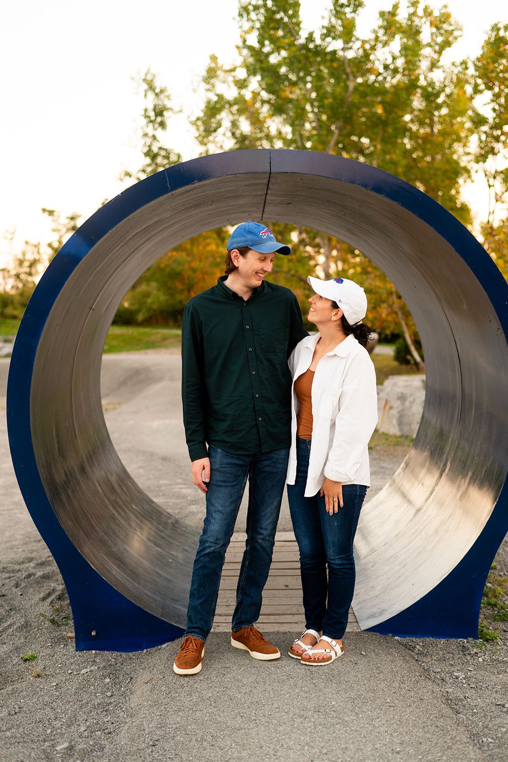 Two people share intimate moments inside a large blue industrial tunnel during an engagement photo session.