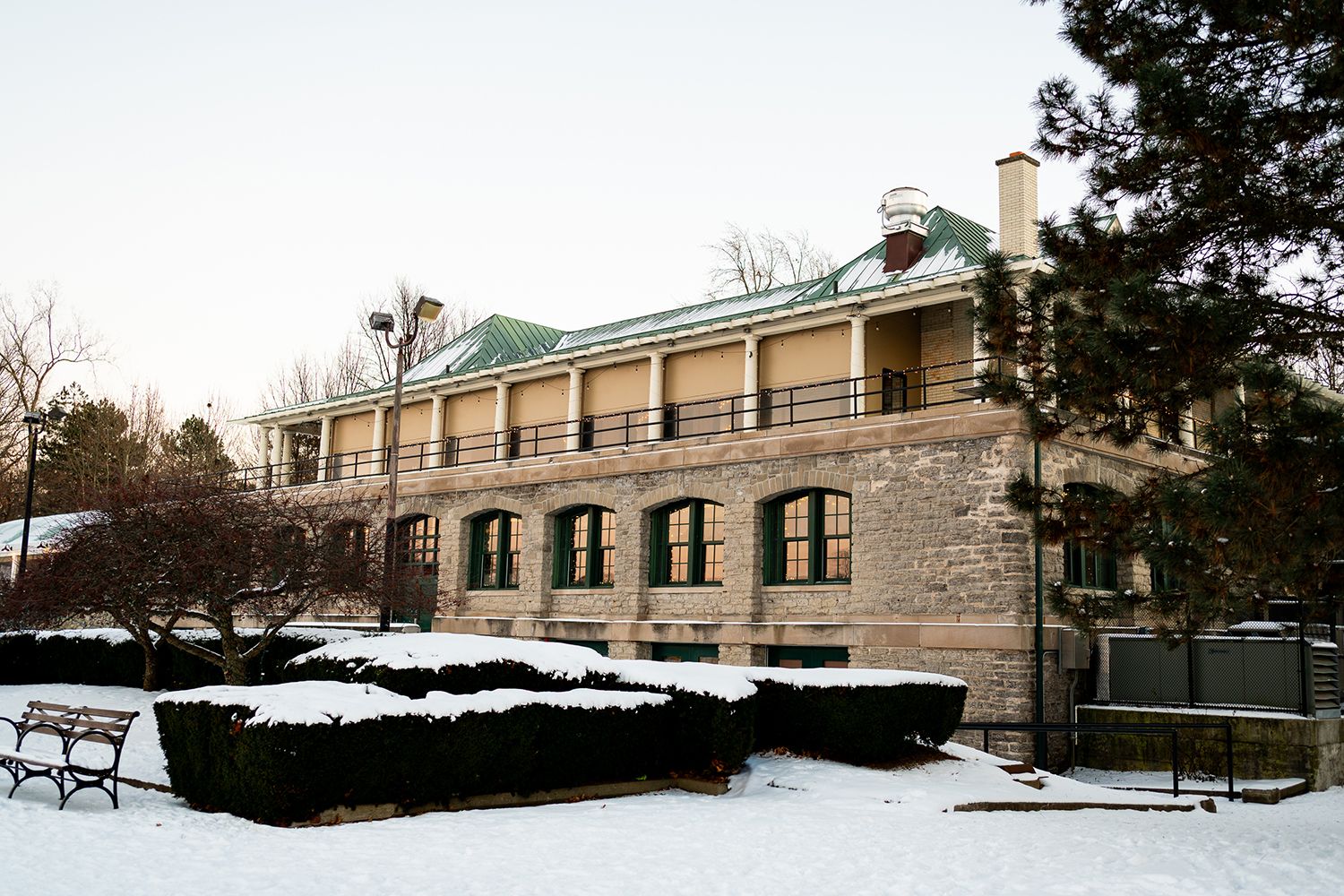 Stone building with architectural columns surrounded by snowy grounds and benches in a winter scene.
