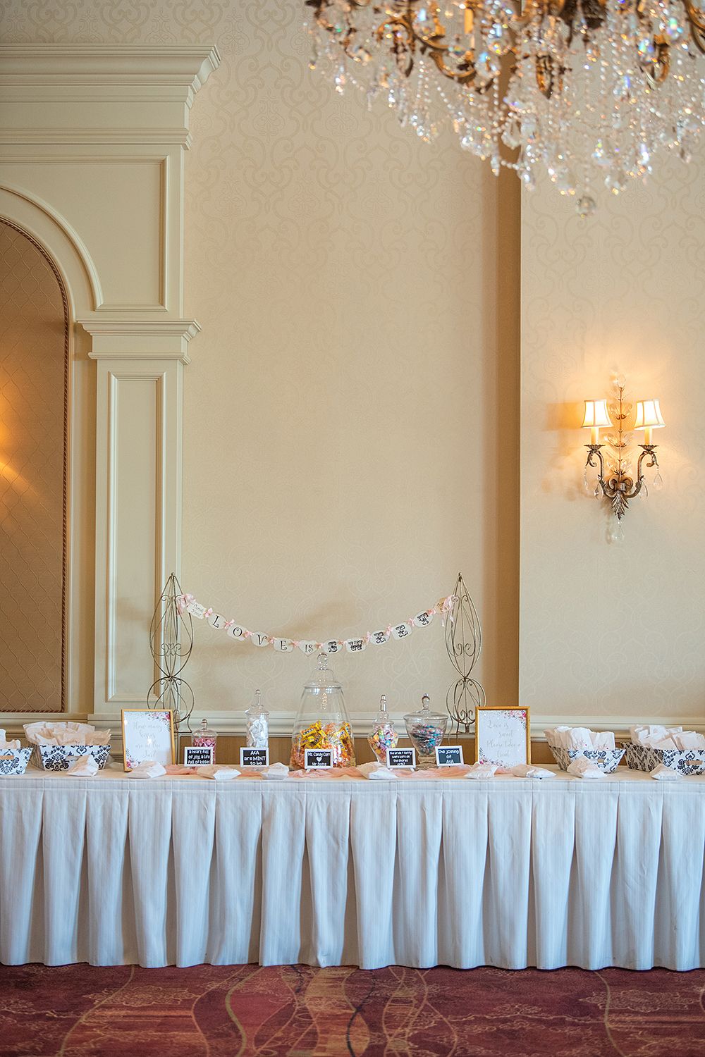 Elegant ballroom with crystal chandeliers and long white-clothed tables set for a wedding reception.