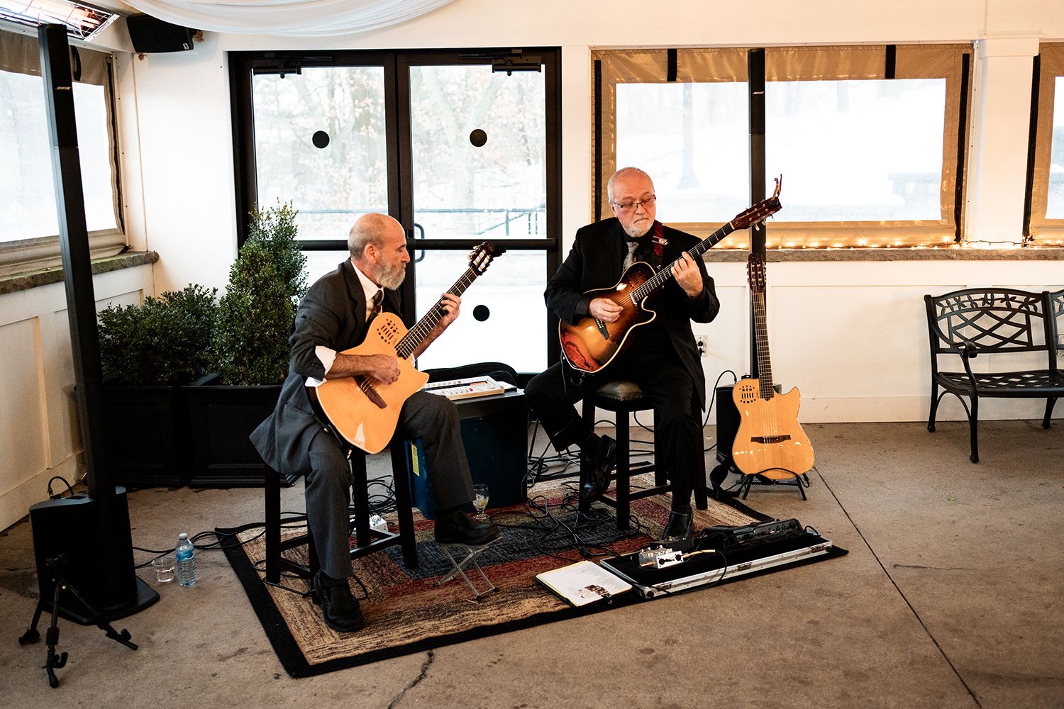 Two musicians perform with acoustic guitars in an intimate indoor venue setting.